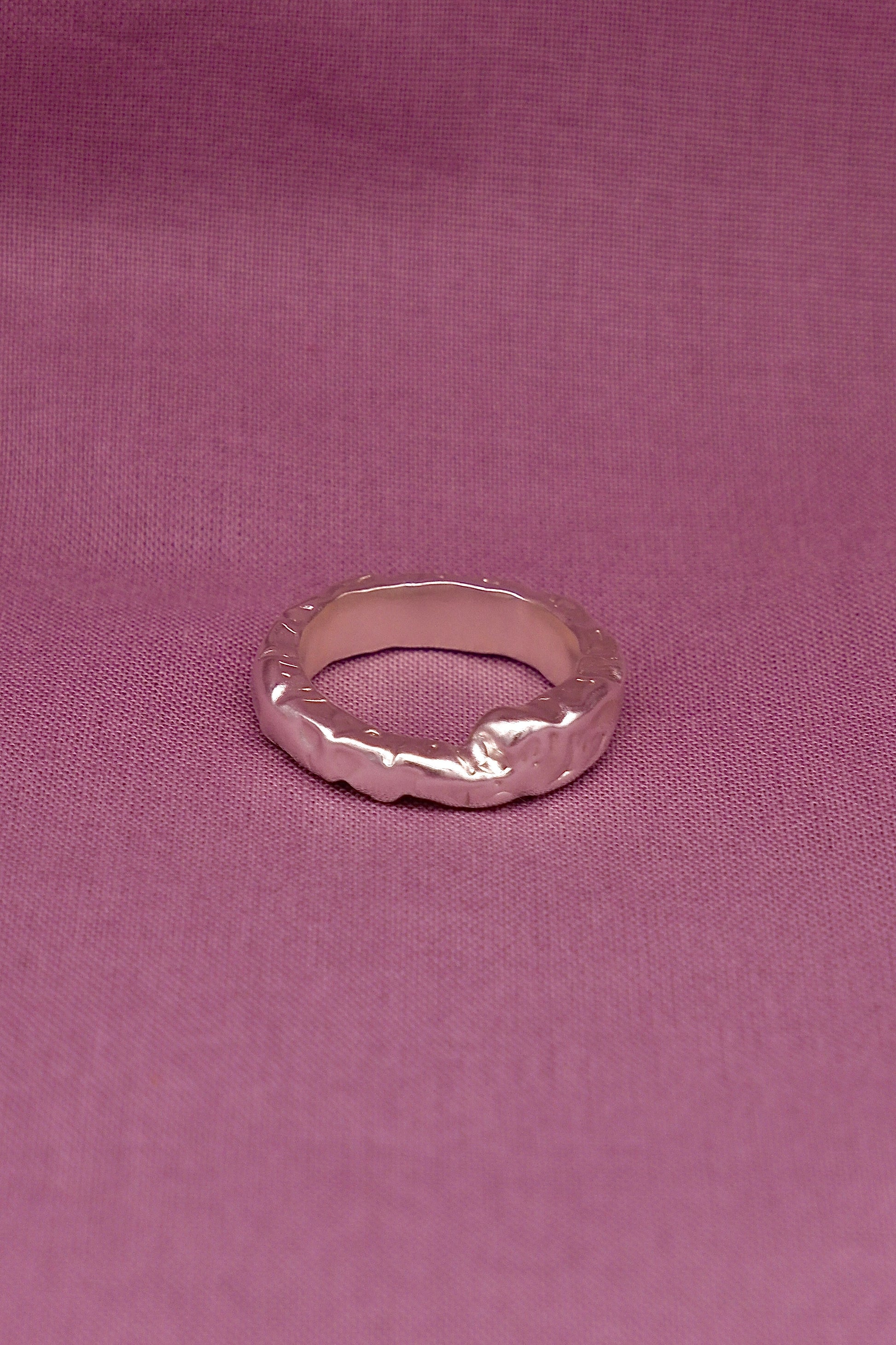 Silver ring on a pink fabric background