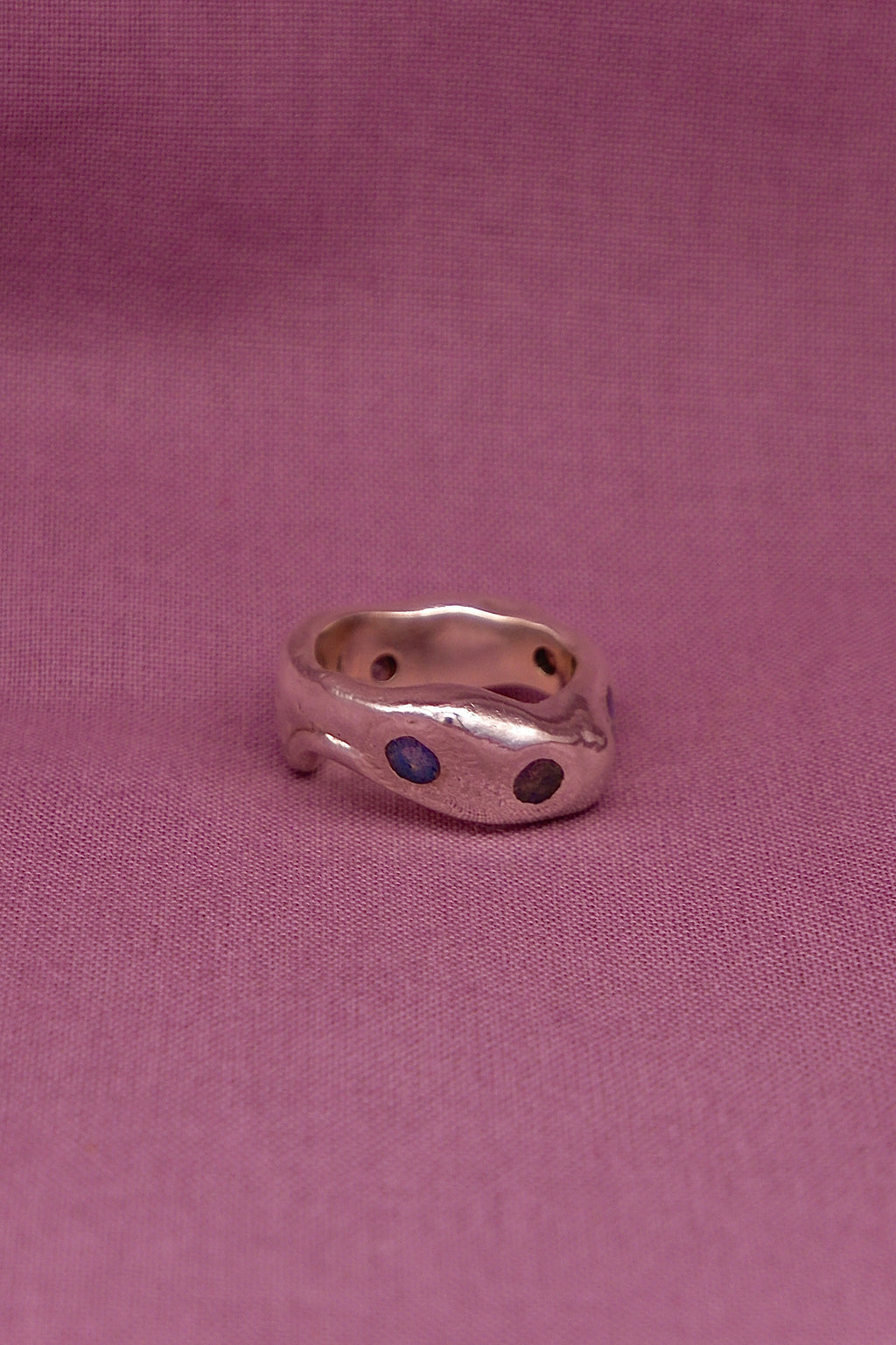 Silver ring with blue stones on a pink fabric background