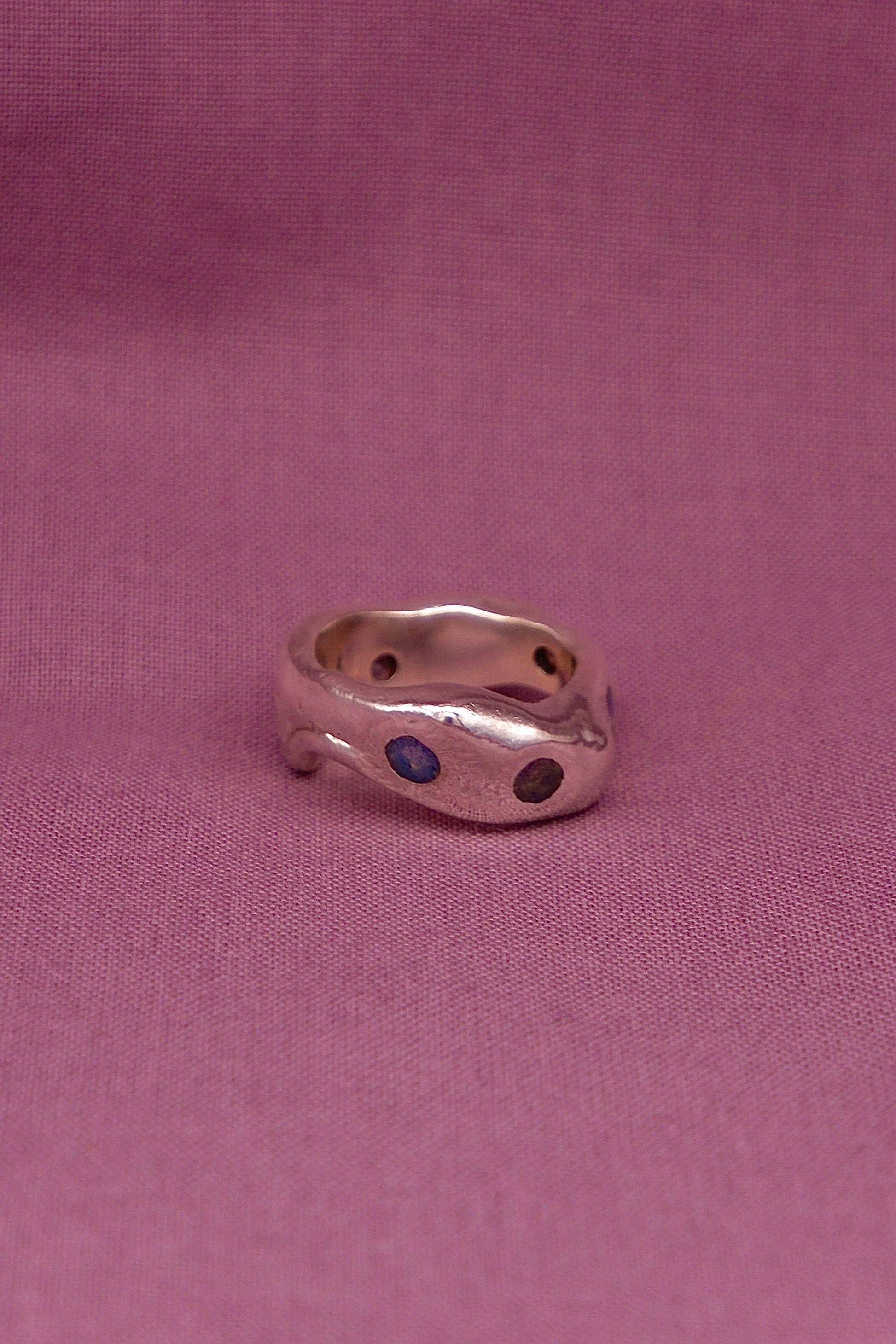 Silver ring with blue stones on a pink fabric background
