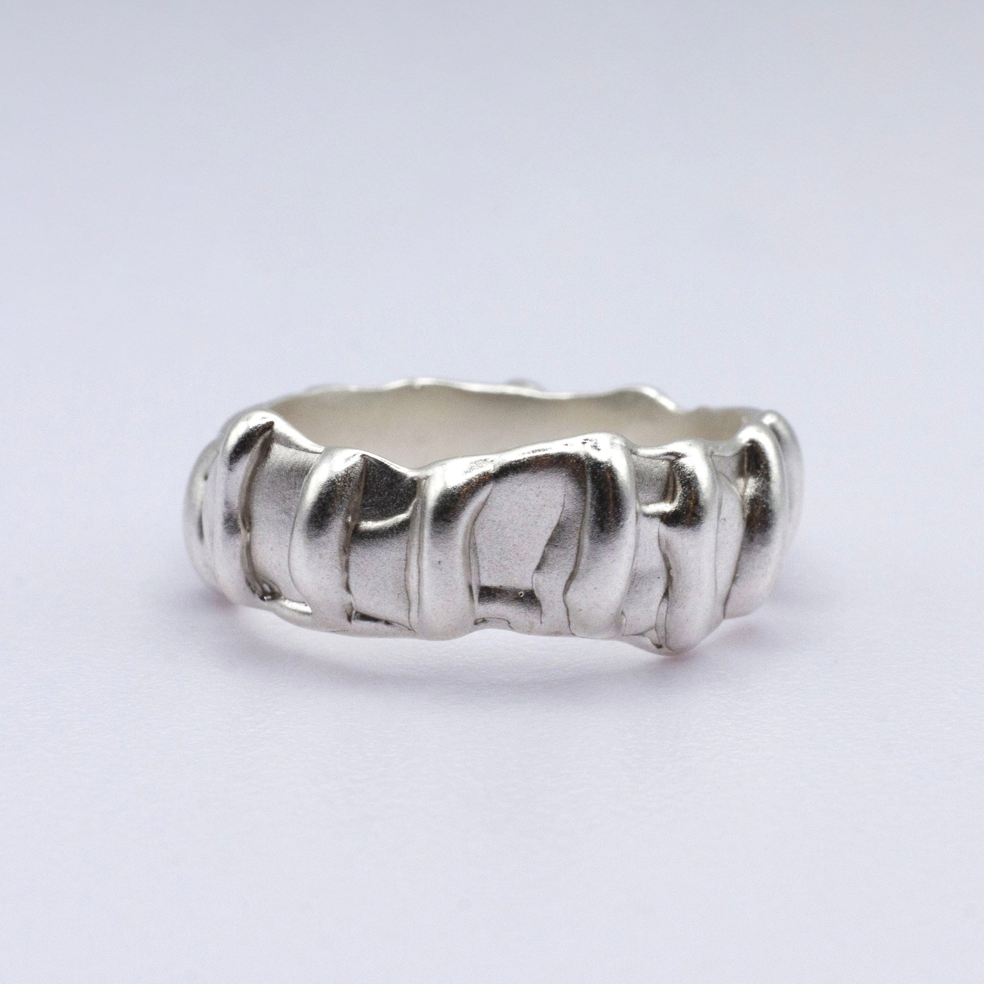 Silver ring with a textured band on a light gray background
