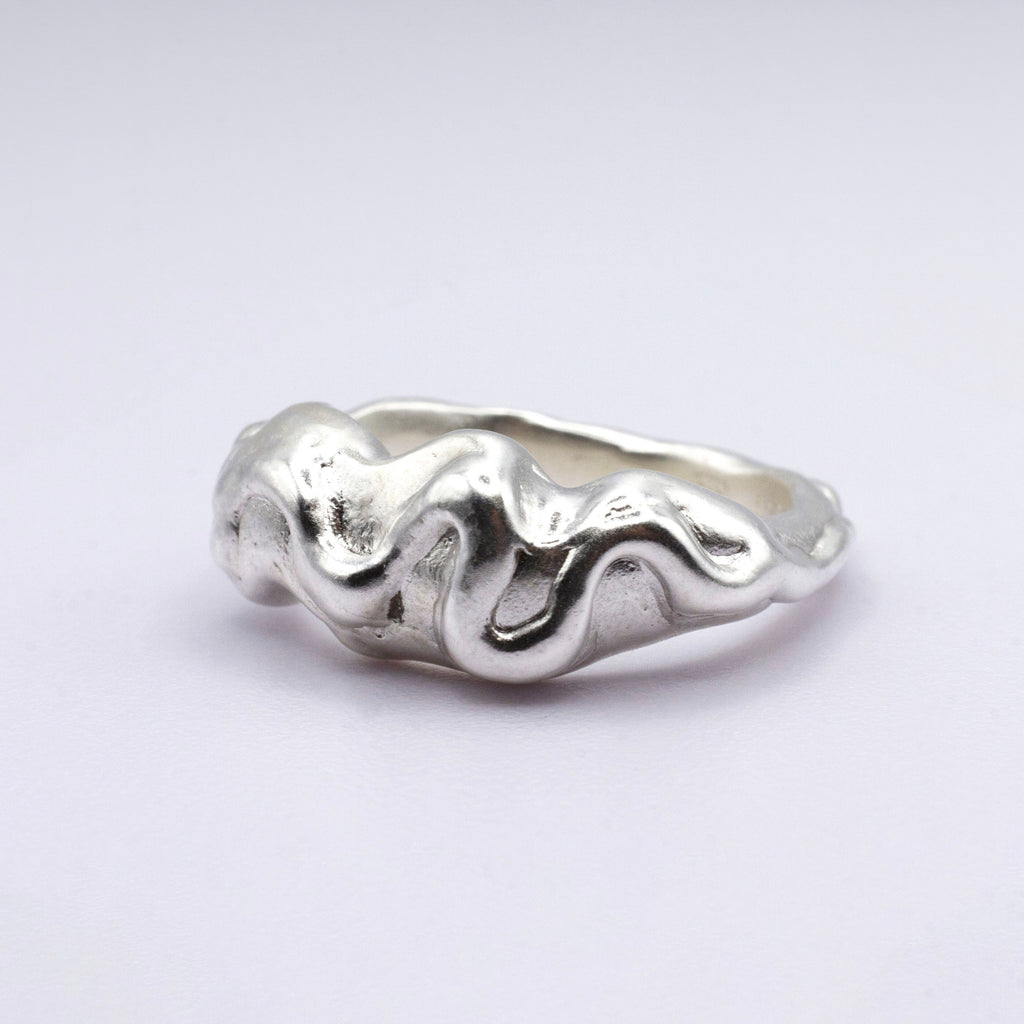 Silver ring with wavy design on a light gray background