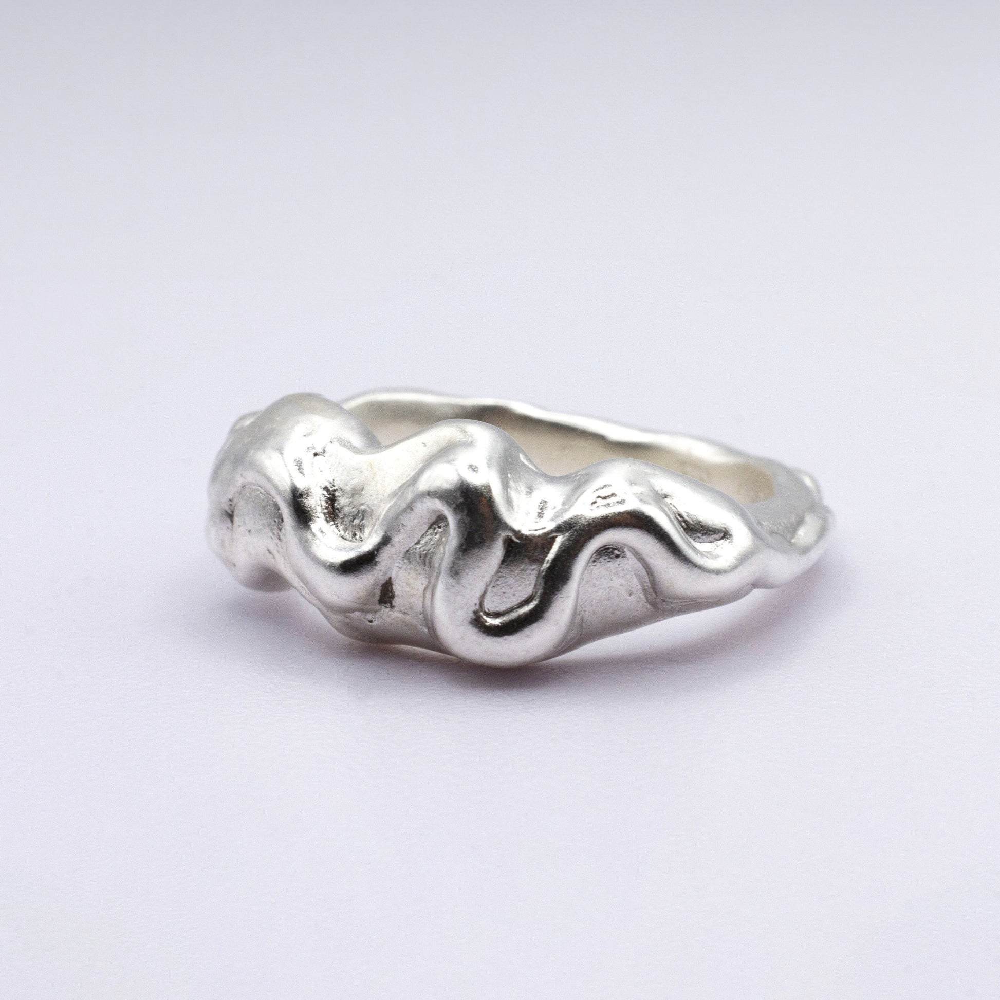 Silver ring with wavy design on a light gray background
