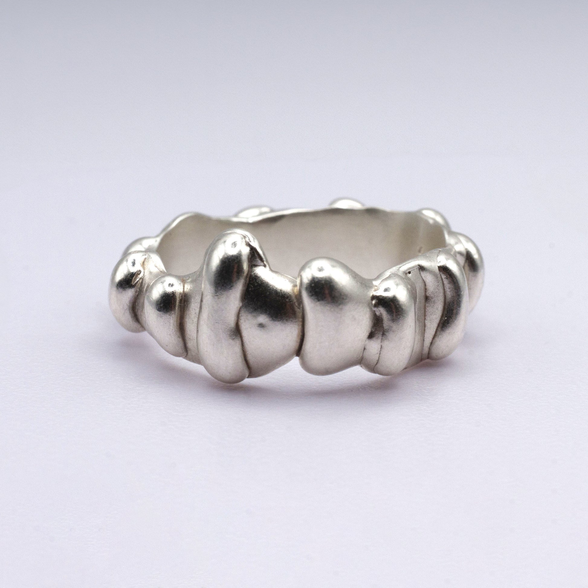 Silver ring with textured design on a light gray background