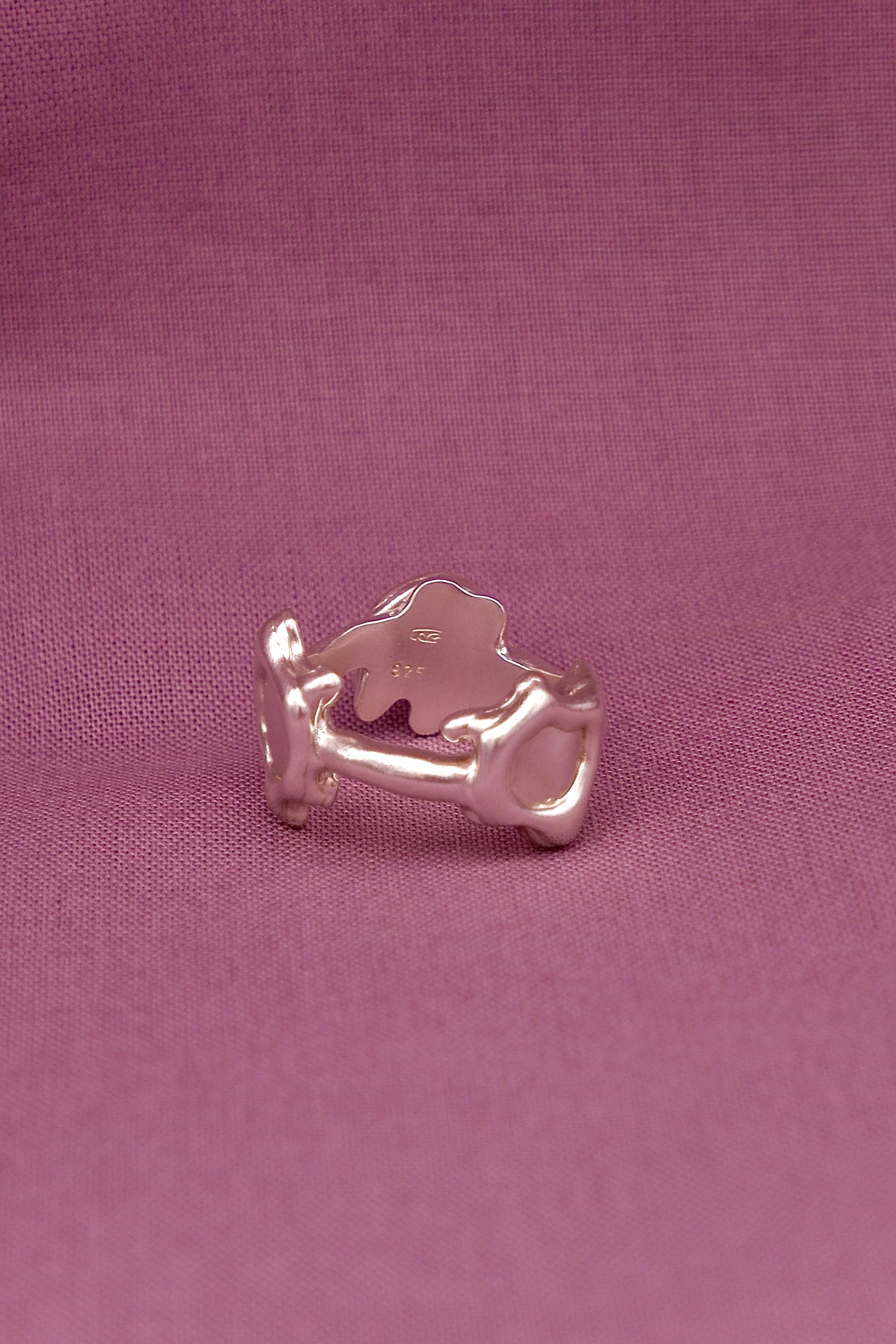 Silver ring with a unique design on a pink fabric background
