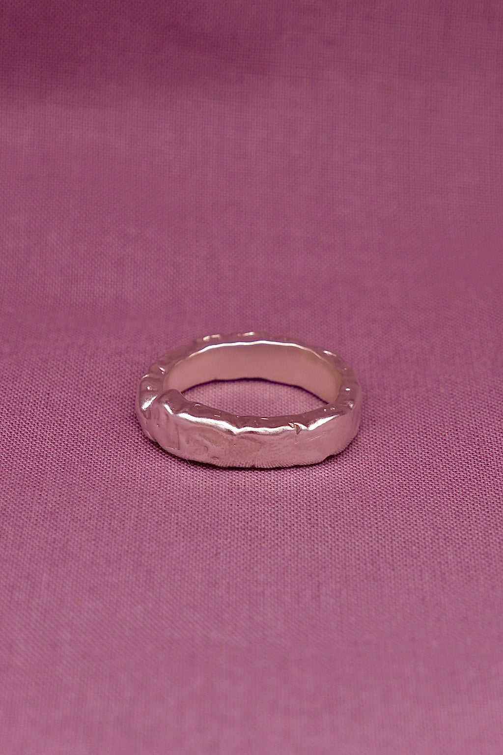 Silver ring on a pink fabric background