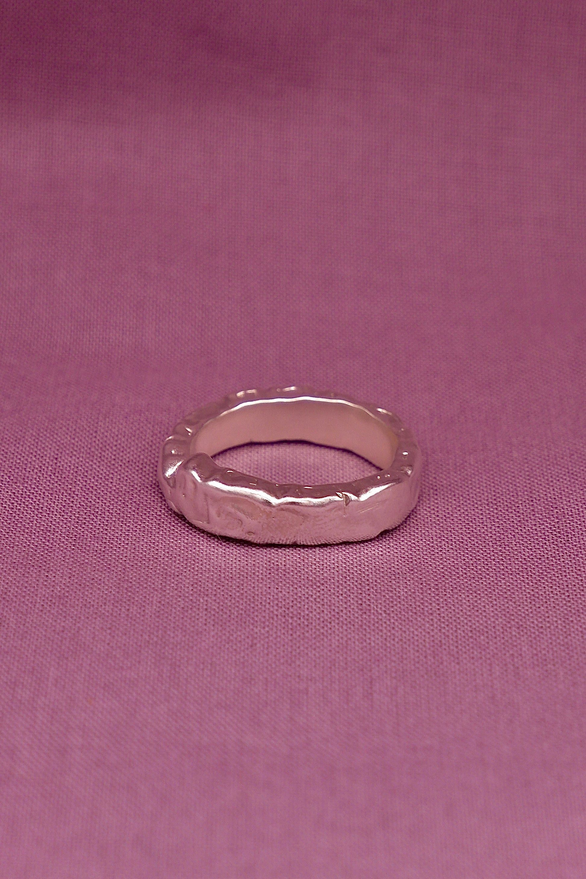 Silver ring on a pink fabric background