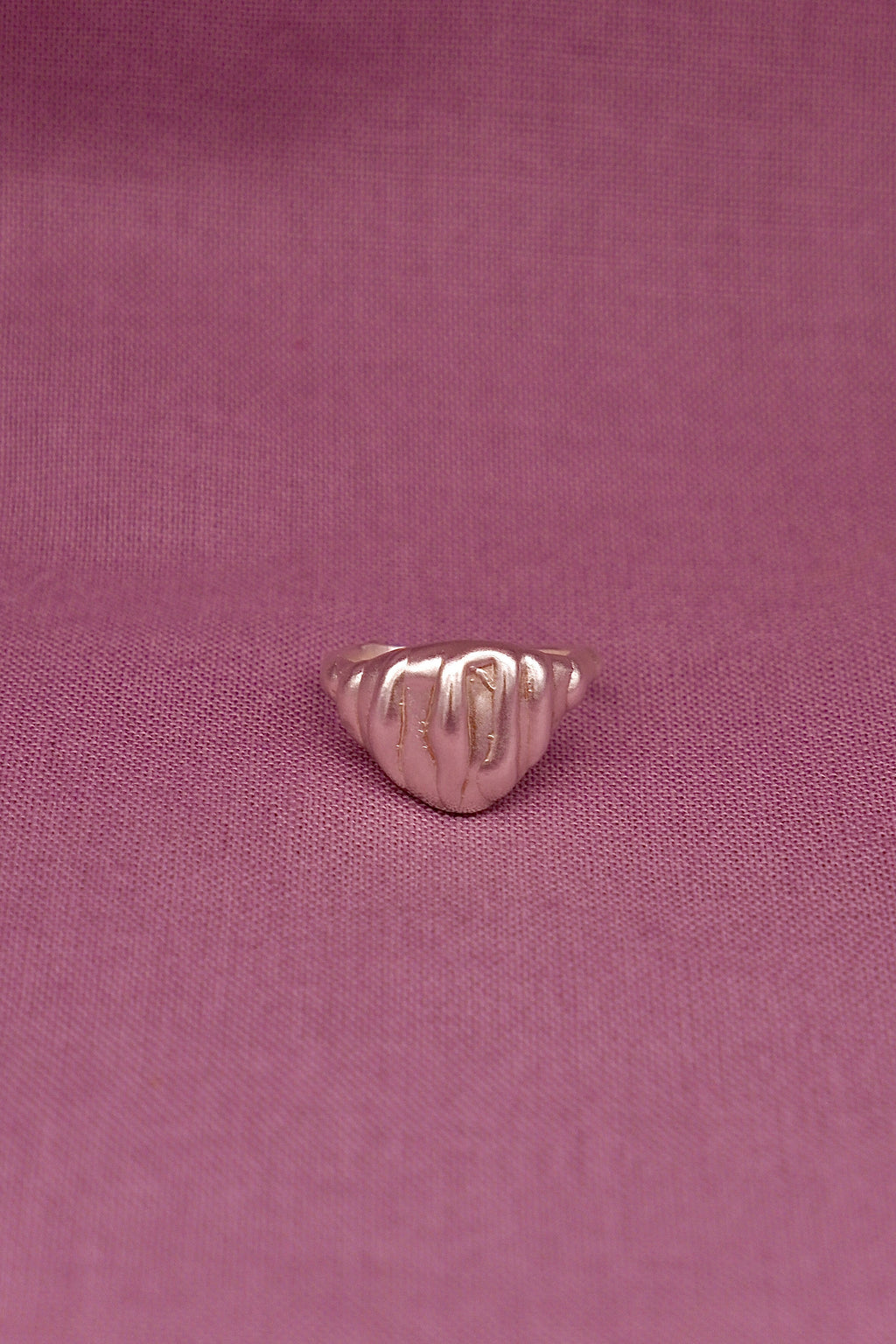 Silver ring on a pink fabric background