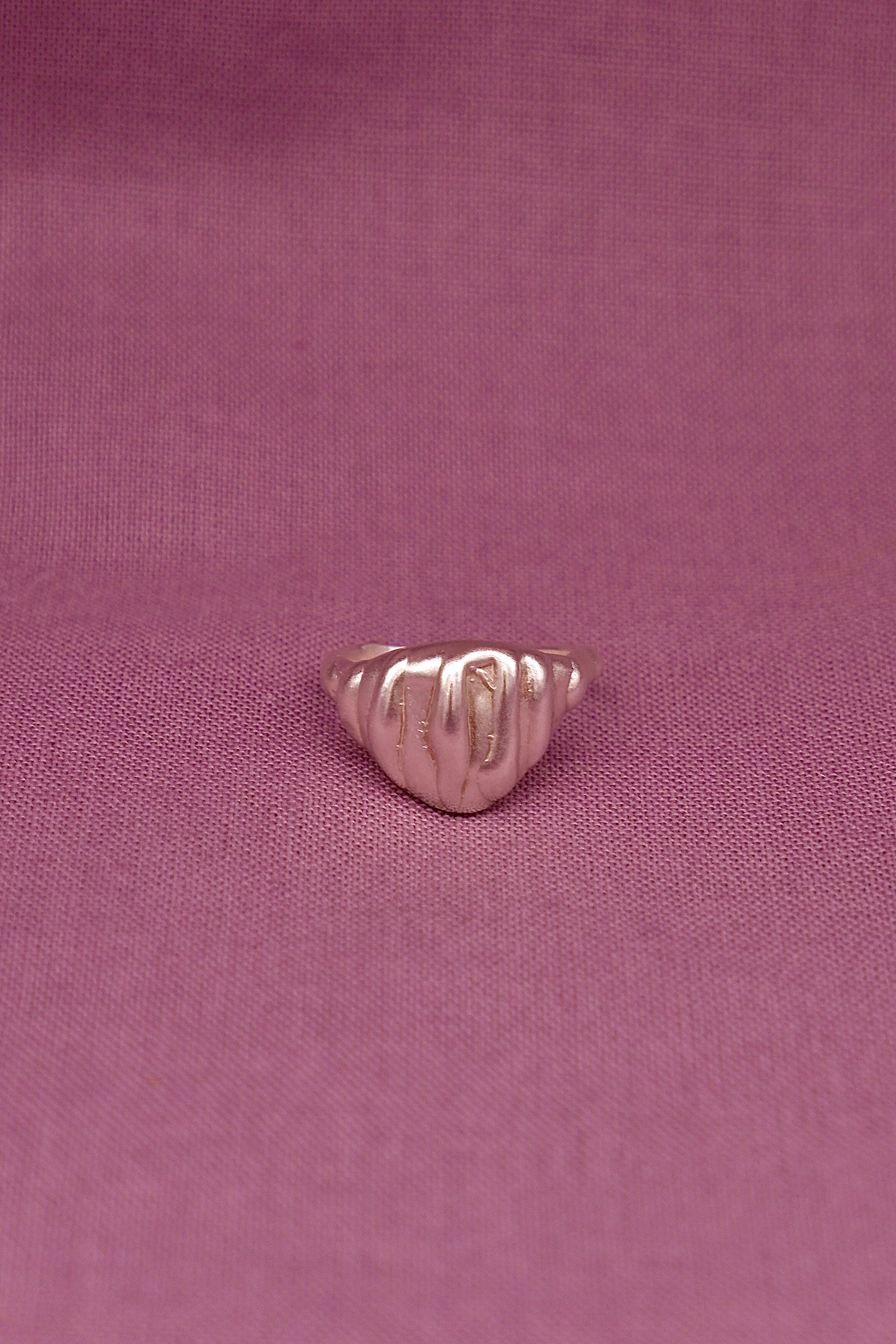 Silver ring on a pink fabric background