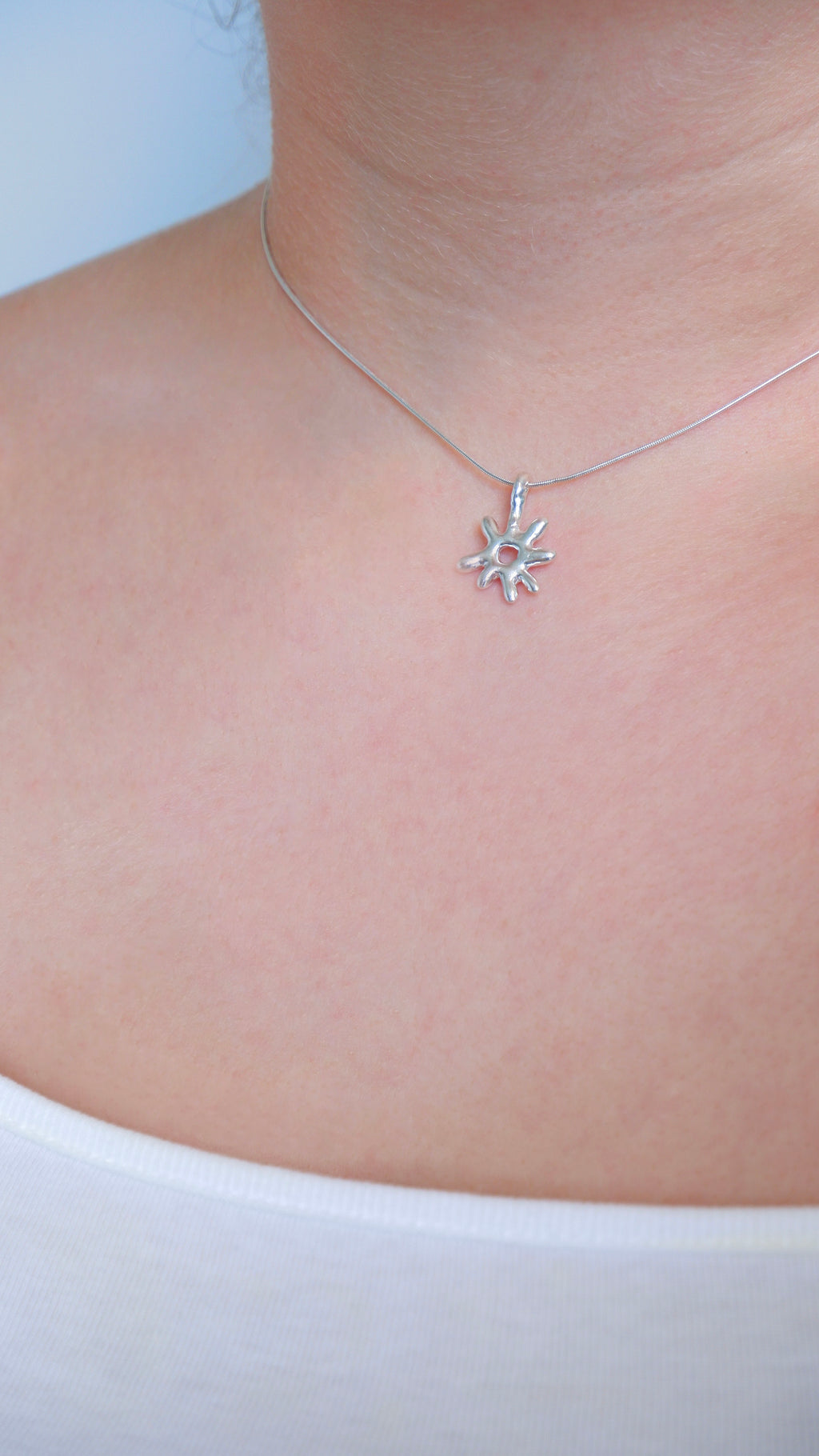 Silver star-shaped necklace on a person's neck against a white background