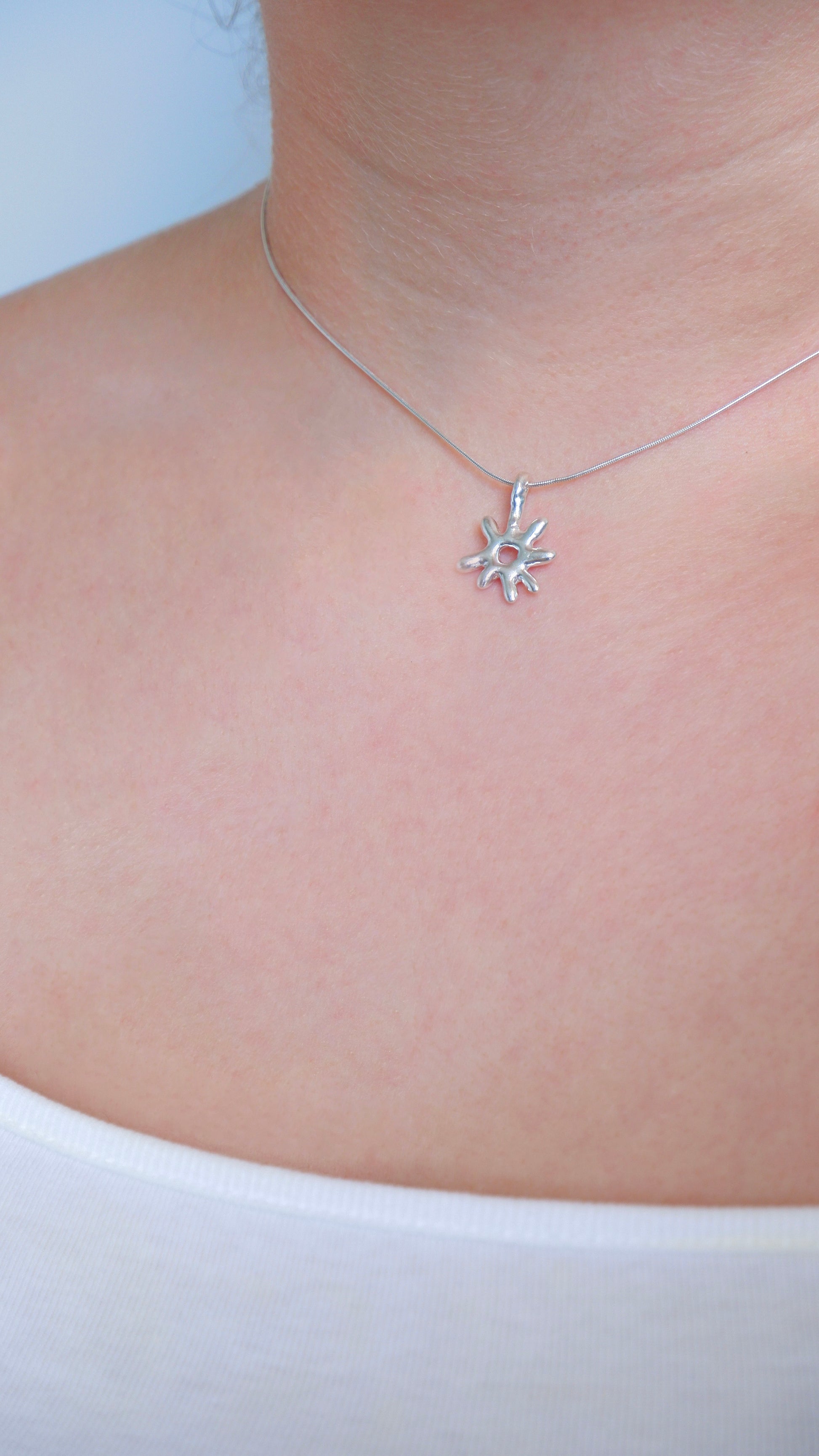 Silver star-shaped necklace on a person's neck against a white background