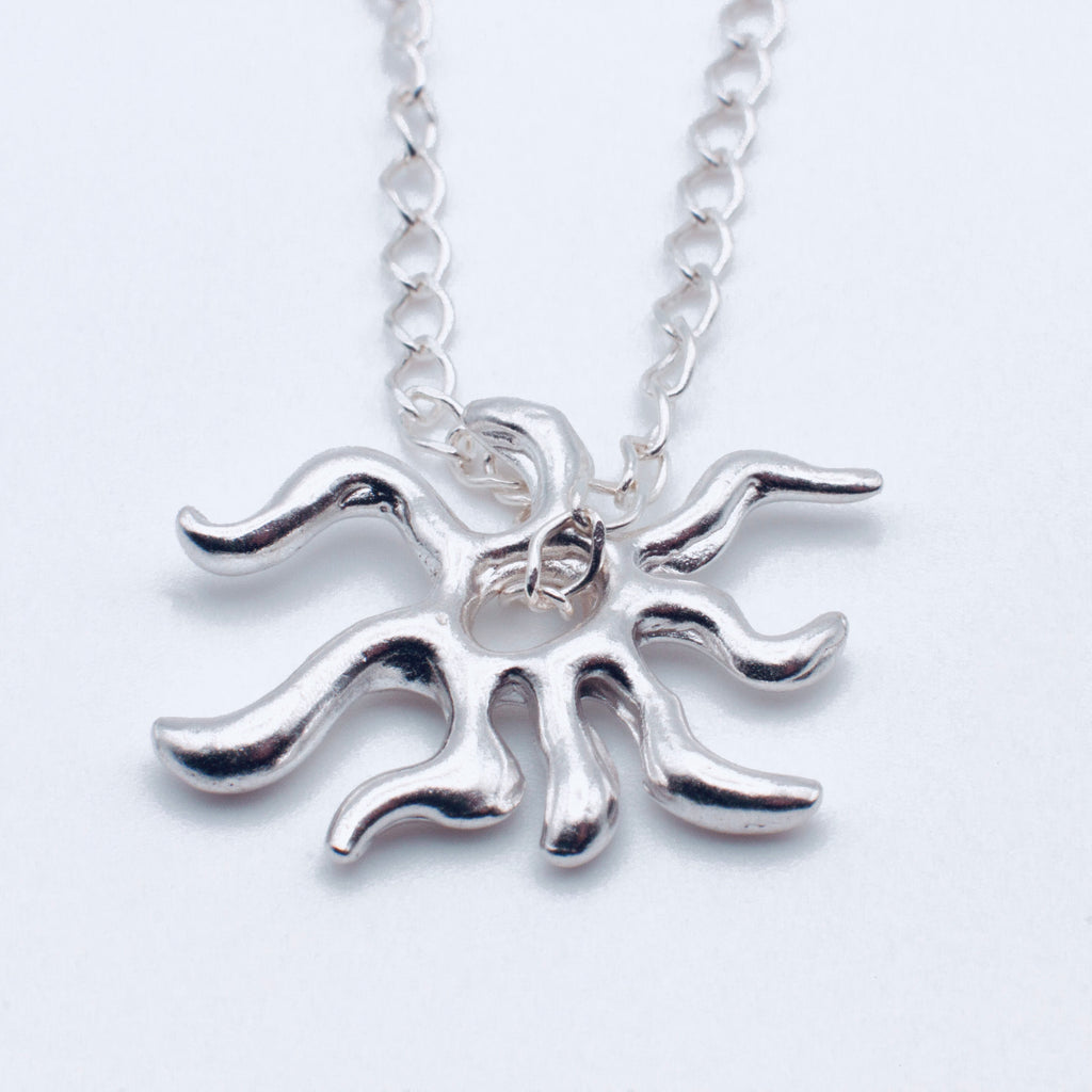 Silver sun-shaped pendant on a chain against a white background