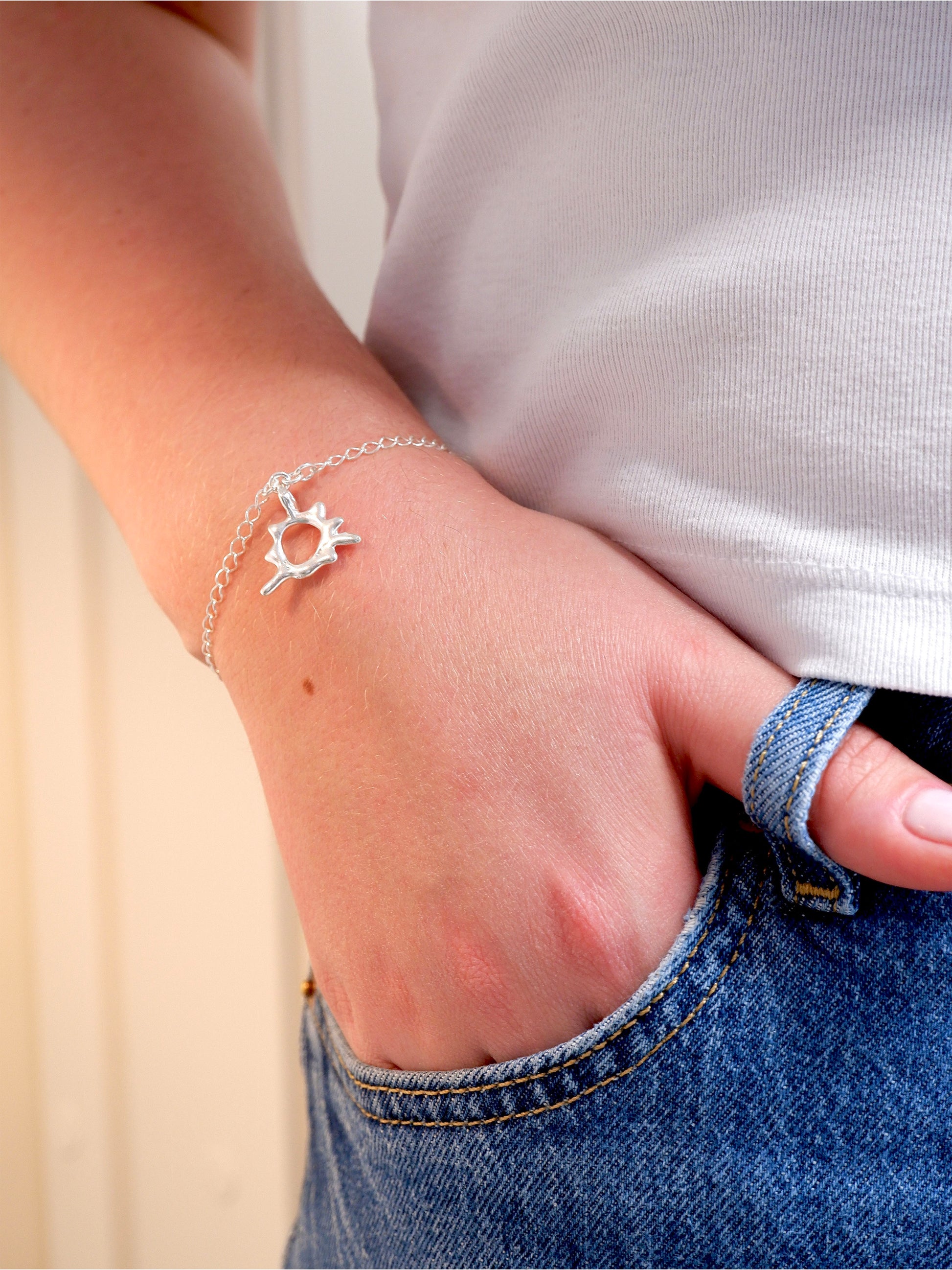 Person wearing a silver bracelet on a plain background