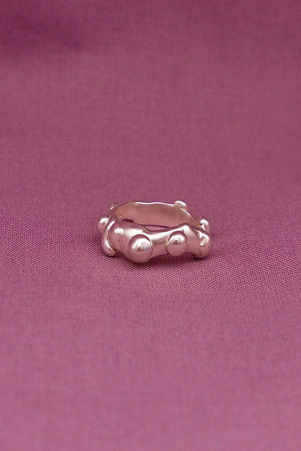 Silver ring with dots on a pink fabric background