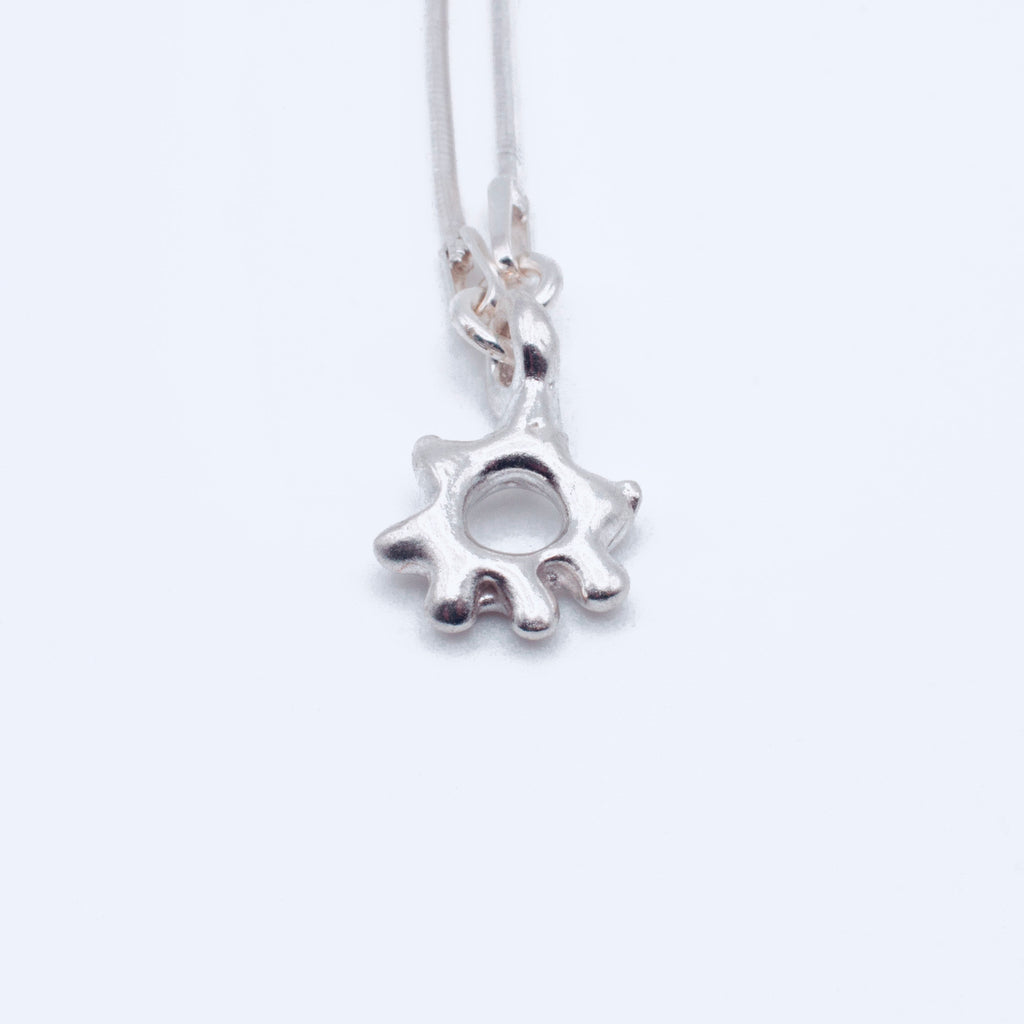 Silver sun-shaped pendant on a white background