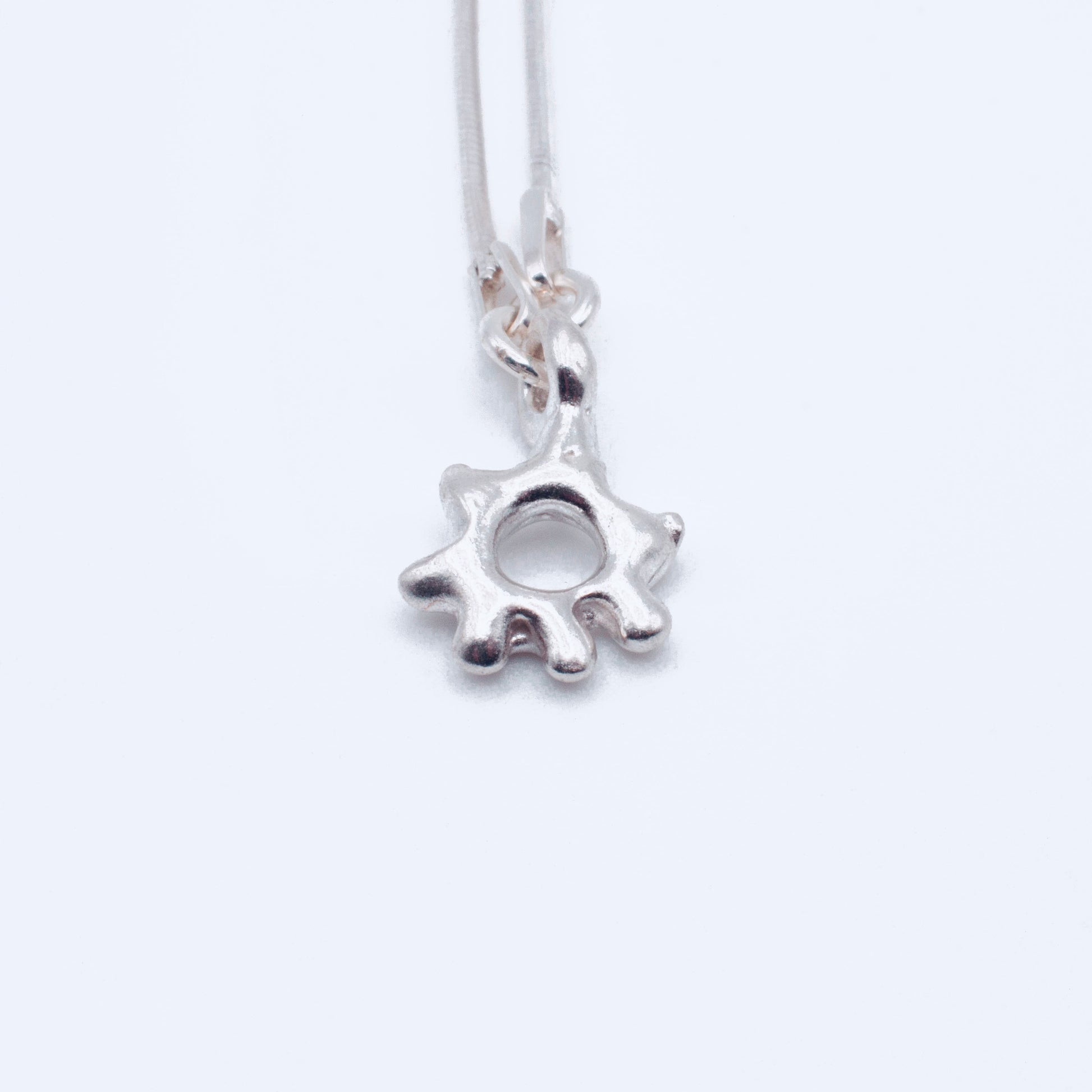 Silver sun-shaped pendant on a white background