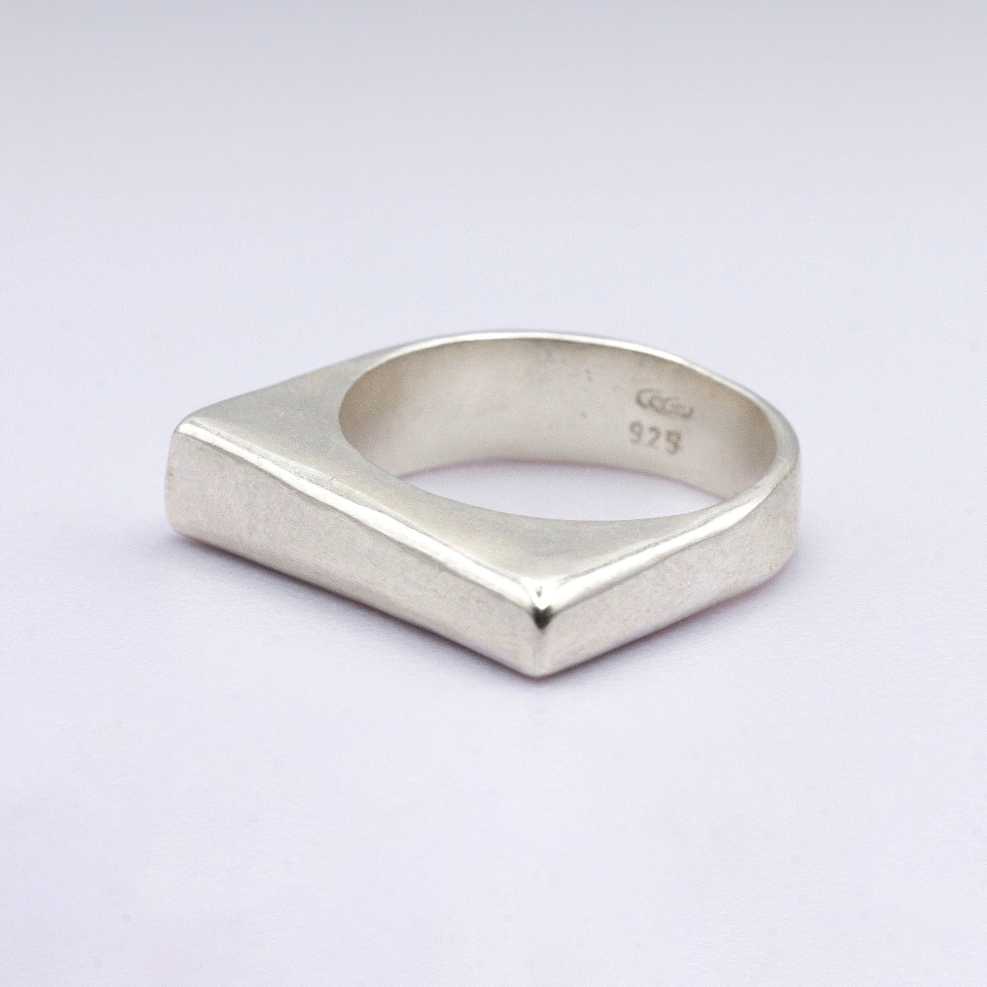 Silver ring with a geometric design on a light gray background