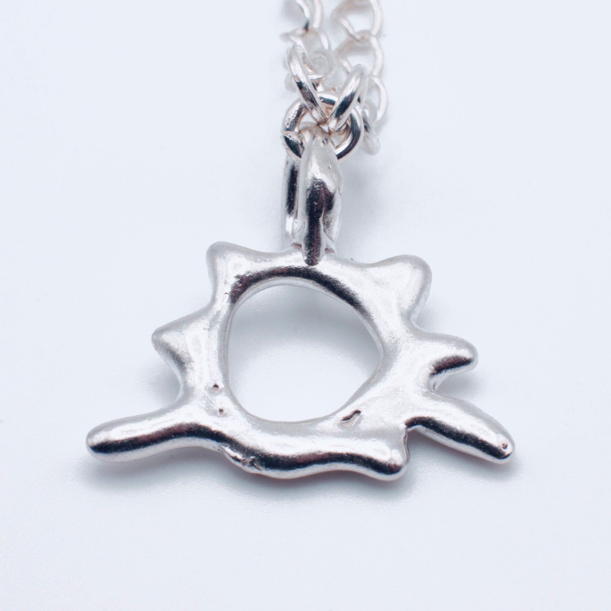 Silver star-shaped pendant on a chain against a white background