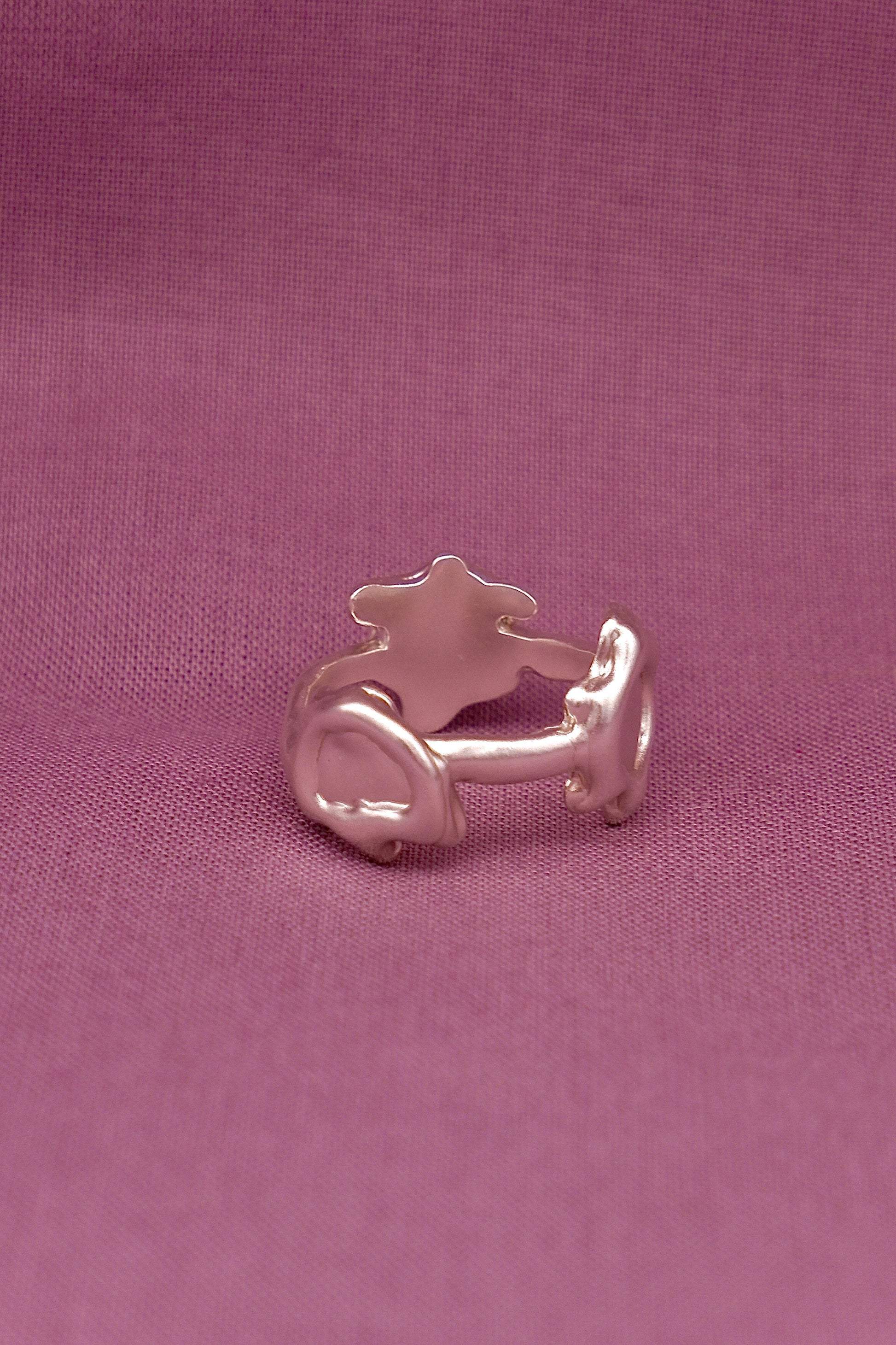 Silver ring with a solar design on a pink fabric background