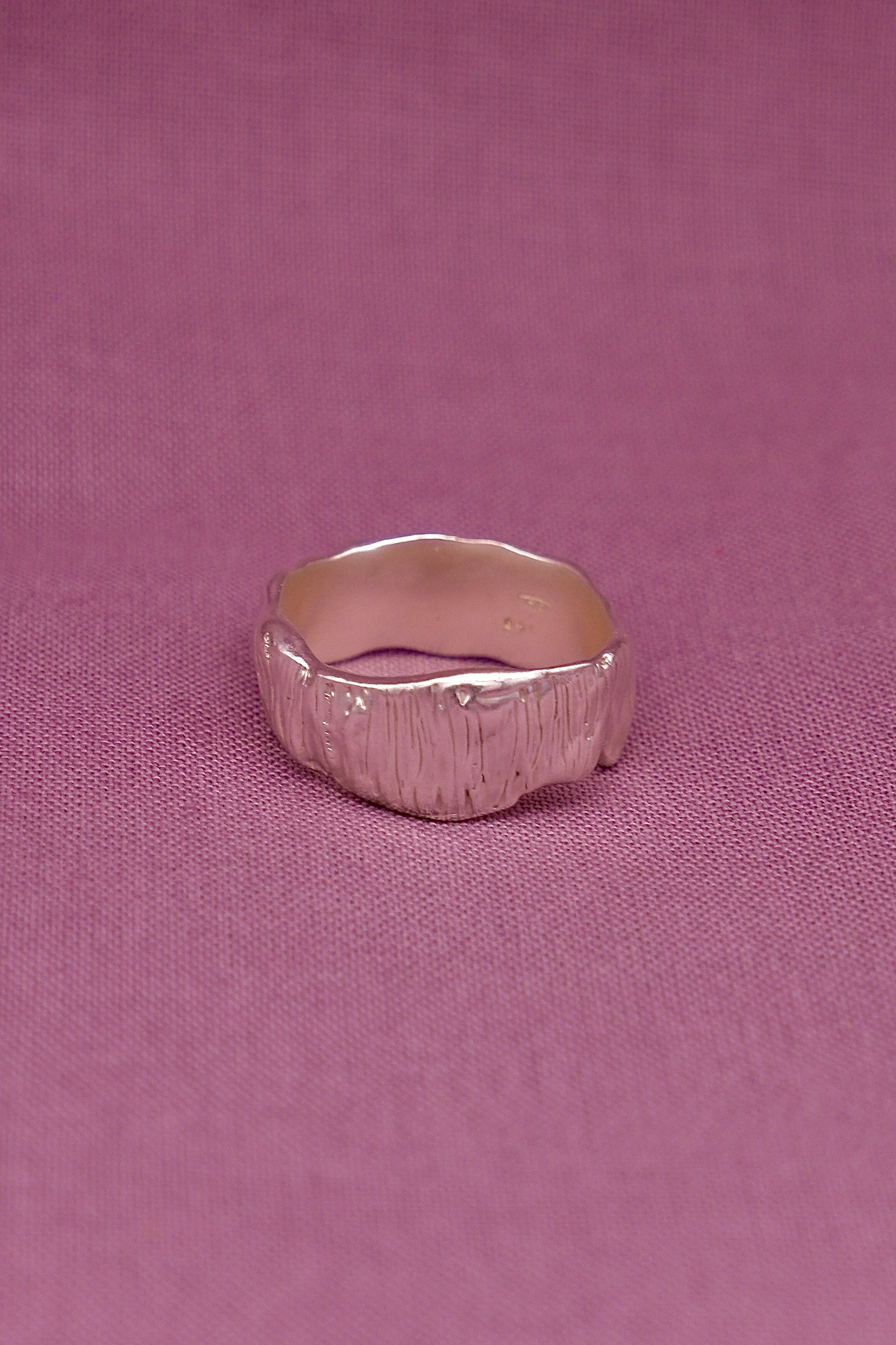 Silver ring on a pink fabric background