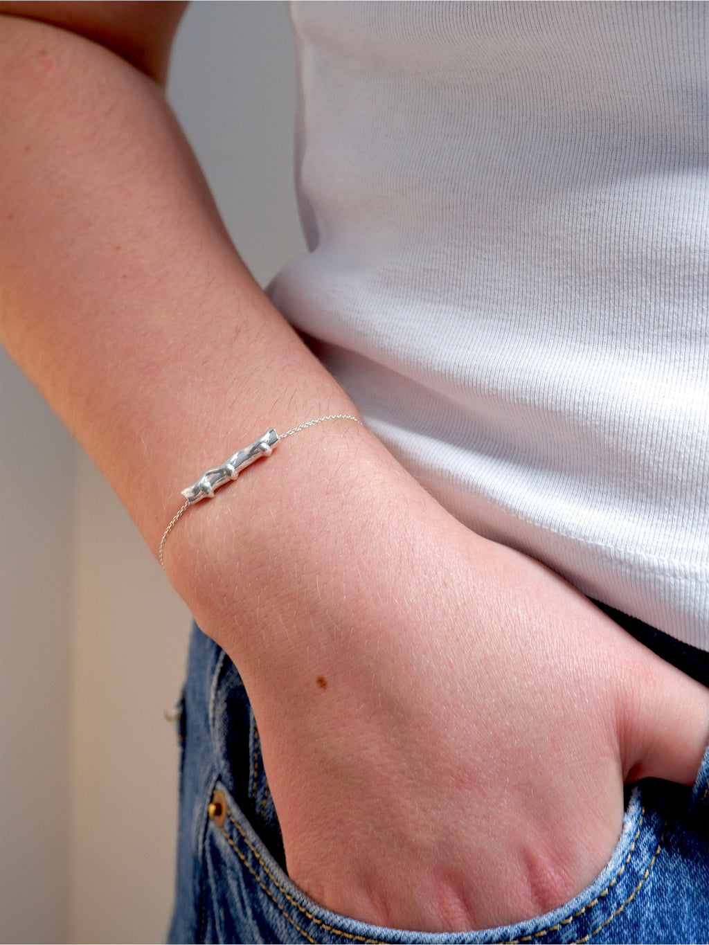 Silver bracelet on a wrist with a neutral background