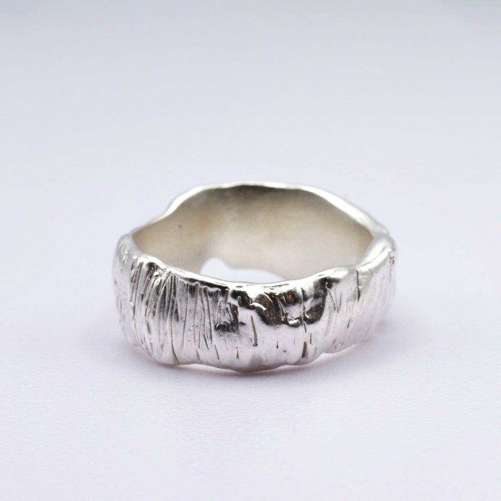 Silver ring with a textured surface on a light gray background