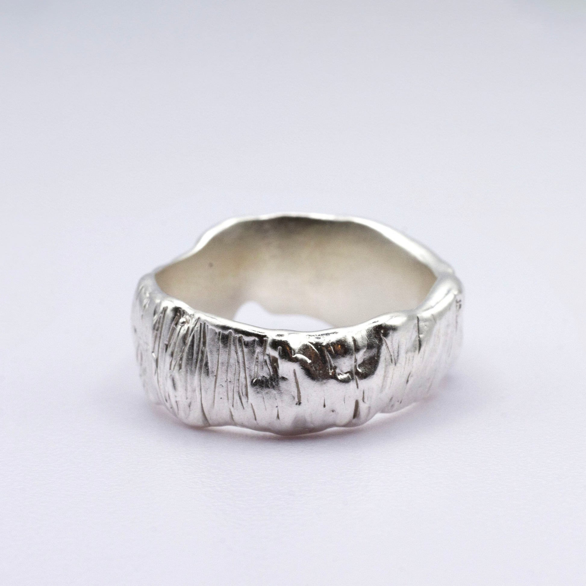 Silver ring with a textured surface on a light gray background