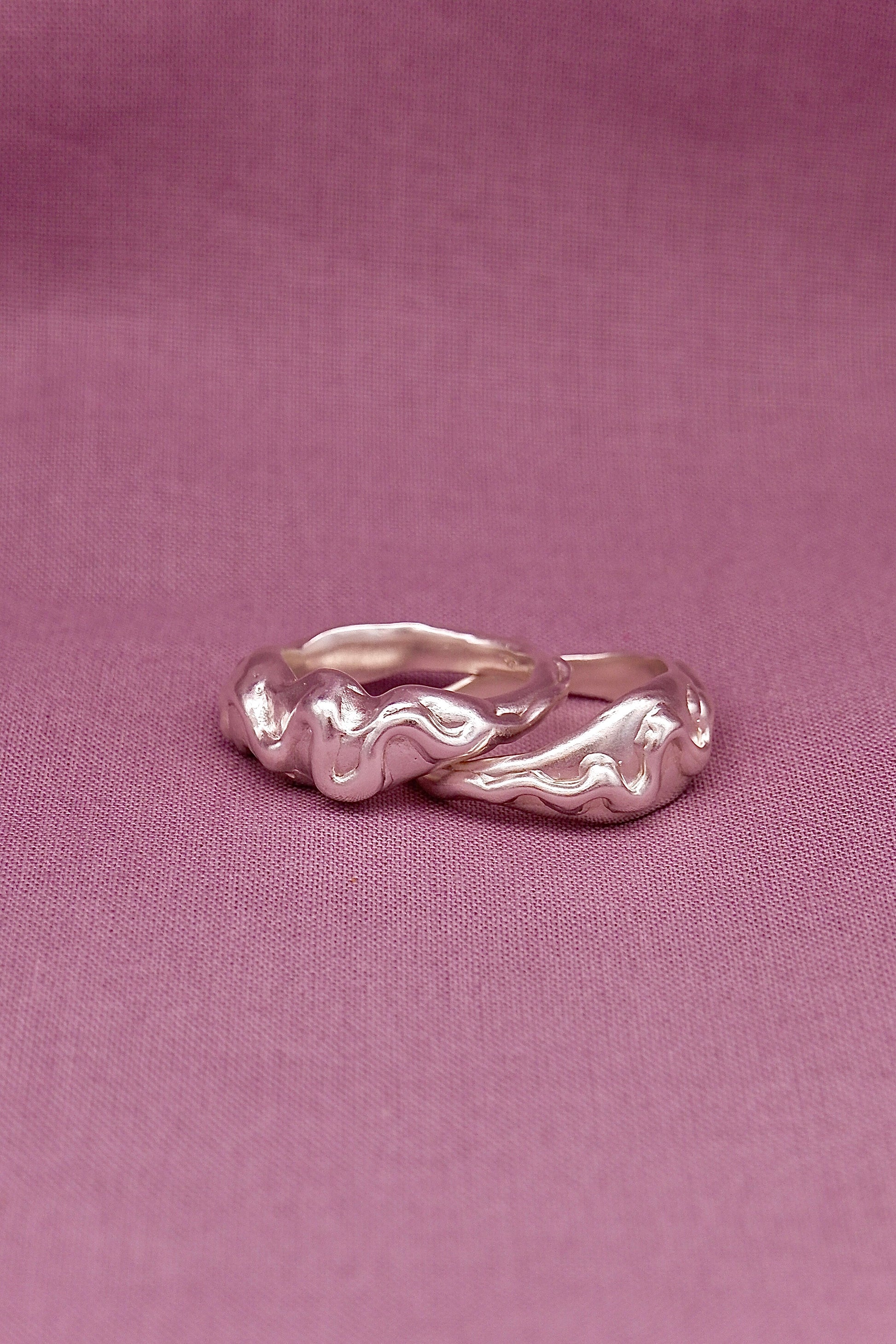 Silver ring with wavy design on a pink background