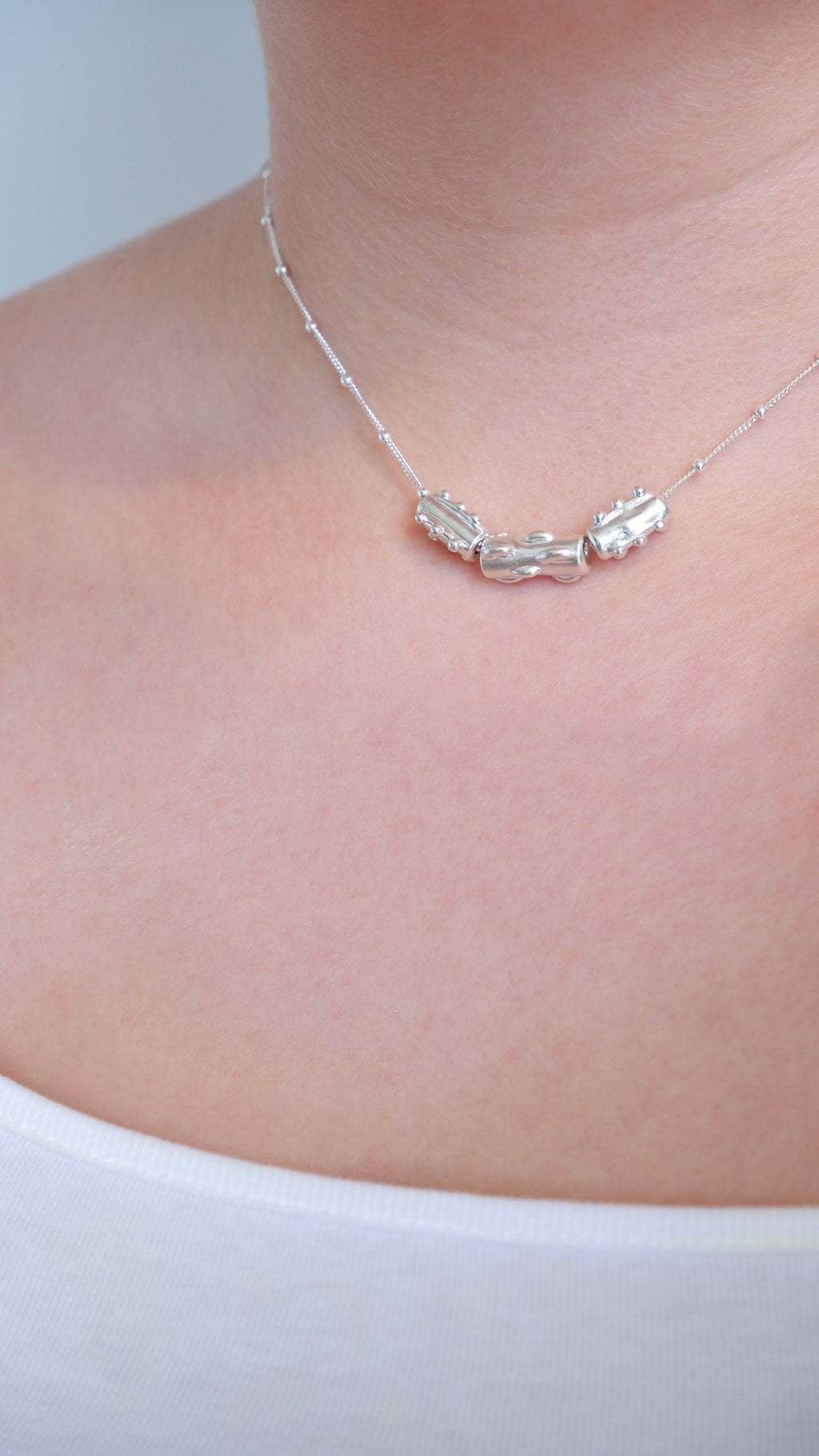 Silver necklace on a person's neck against a white background