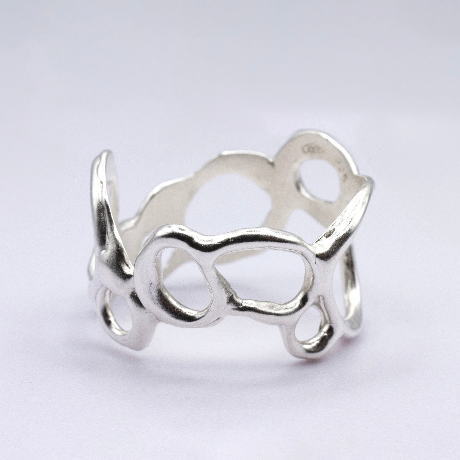 Silver ring with a unique design on a light gray background