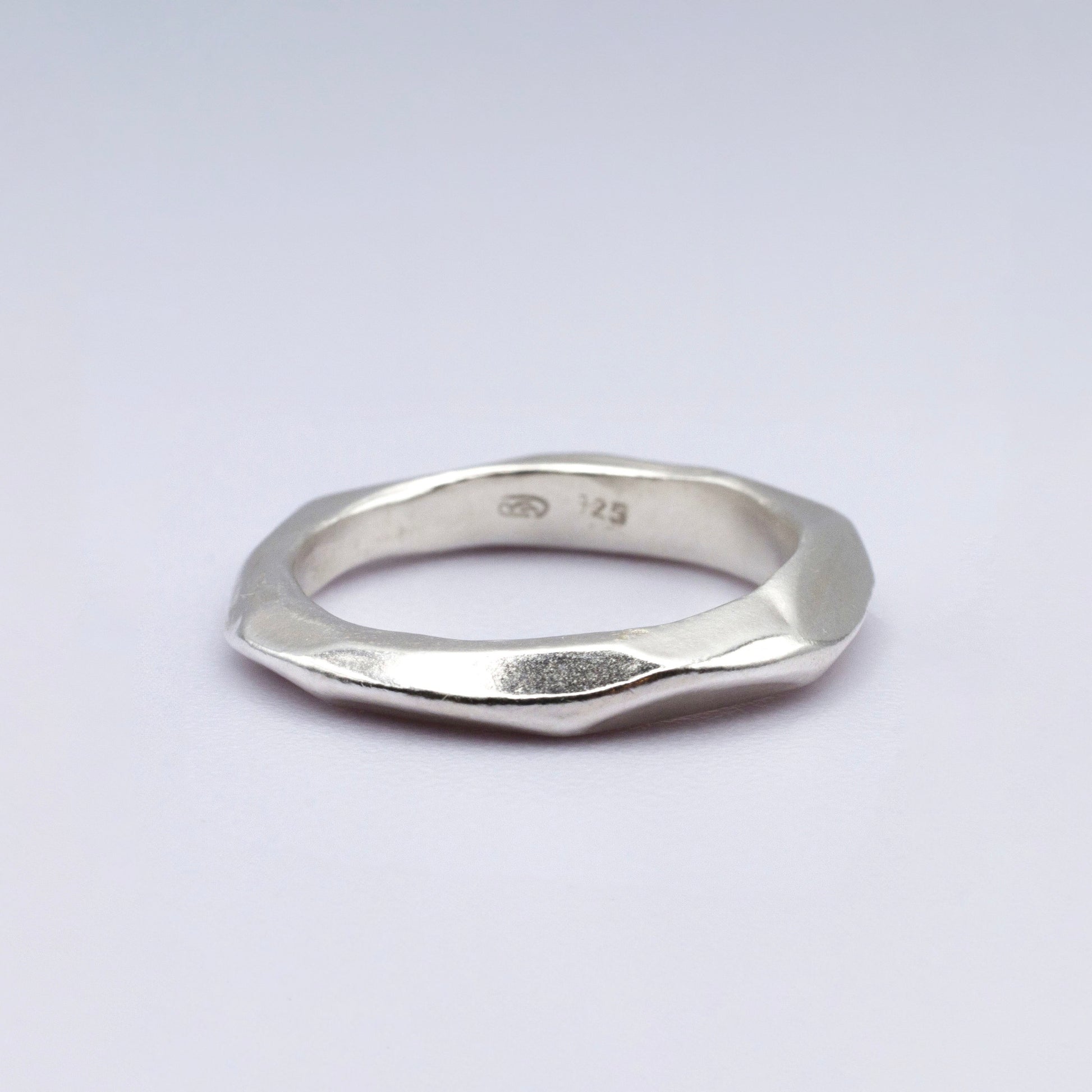 Silver ring with geometric design on a light gray background