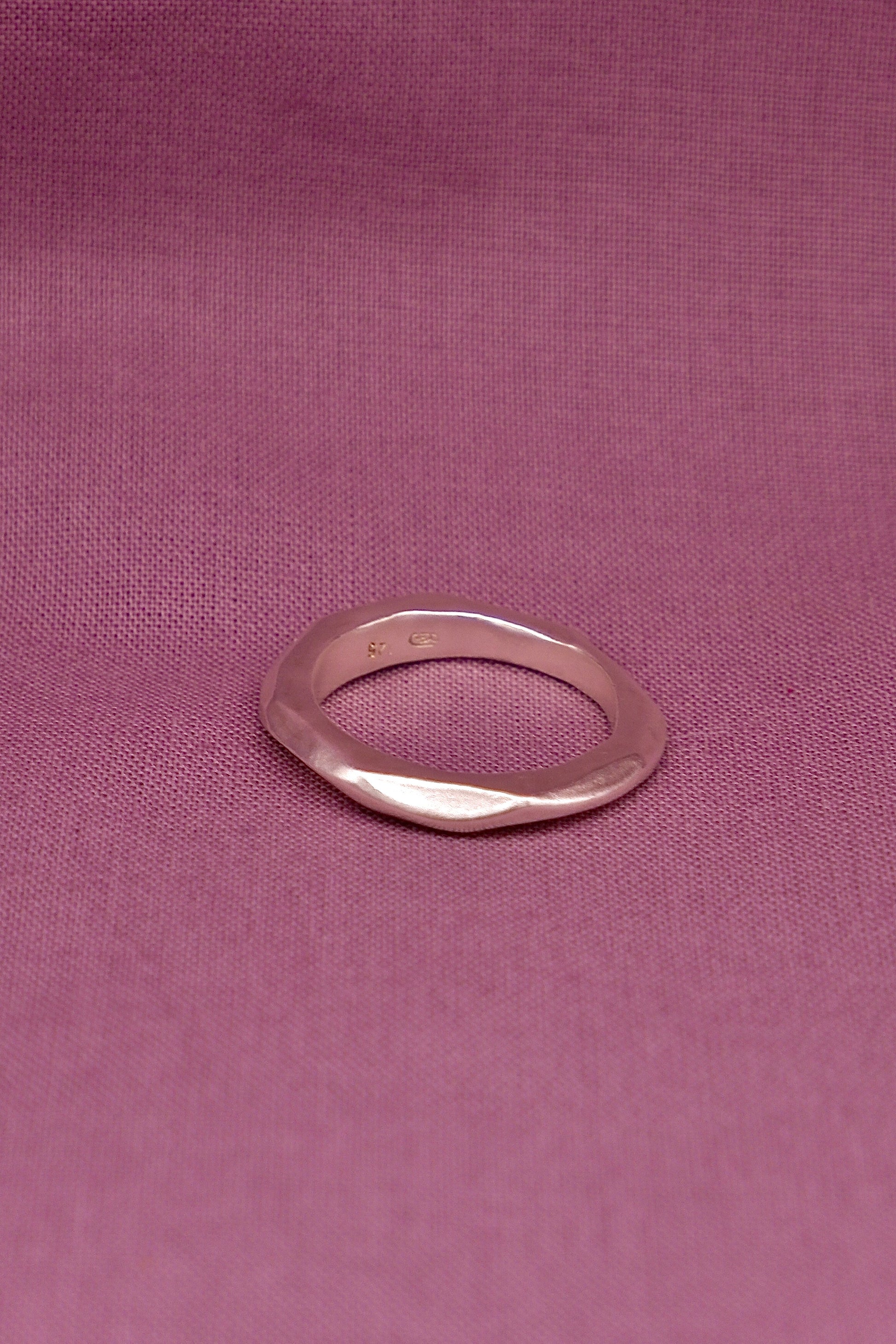 Silver ring on a pink fabric background