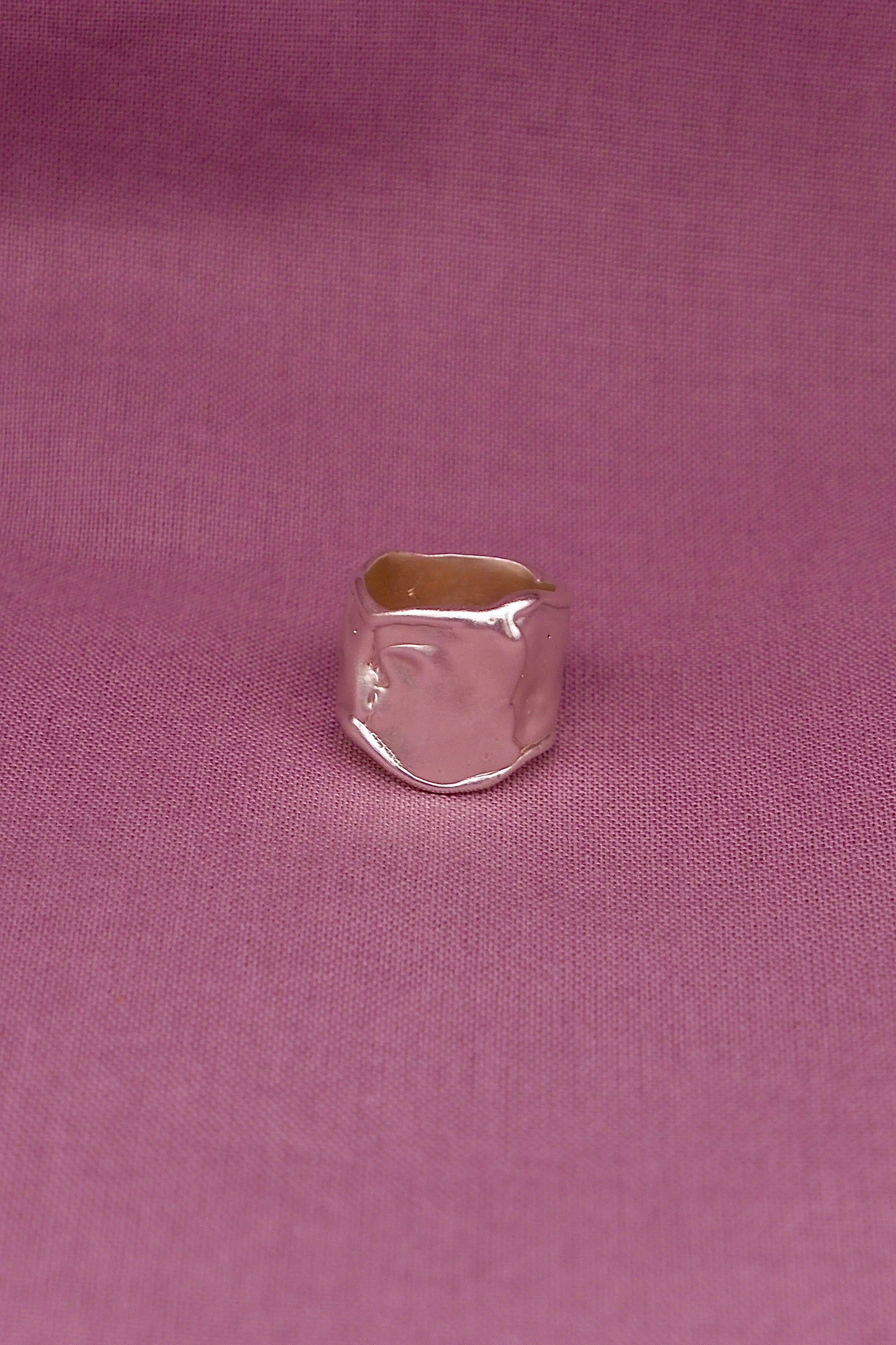 Silver ring on a pink fabric background