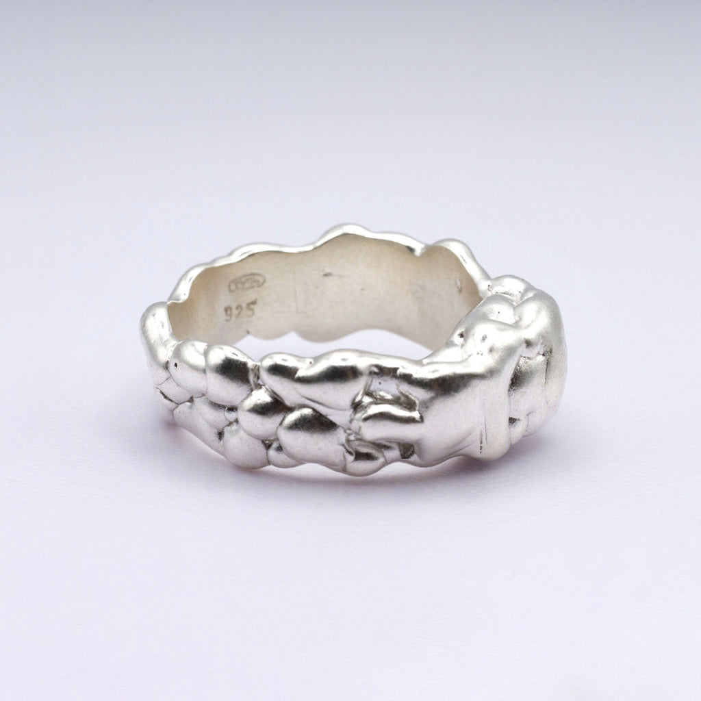 Silver ring with textured design on a light gray background