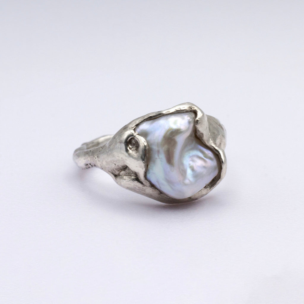 Silver ring with a large pearl on a white background