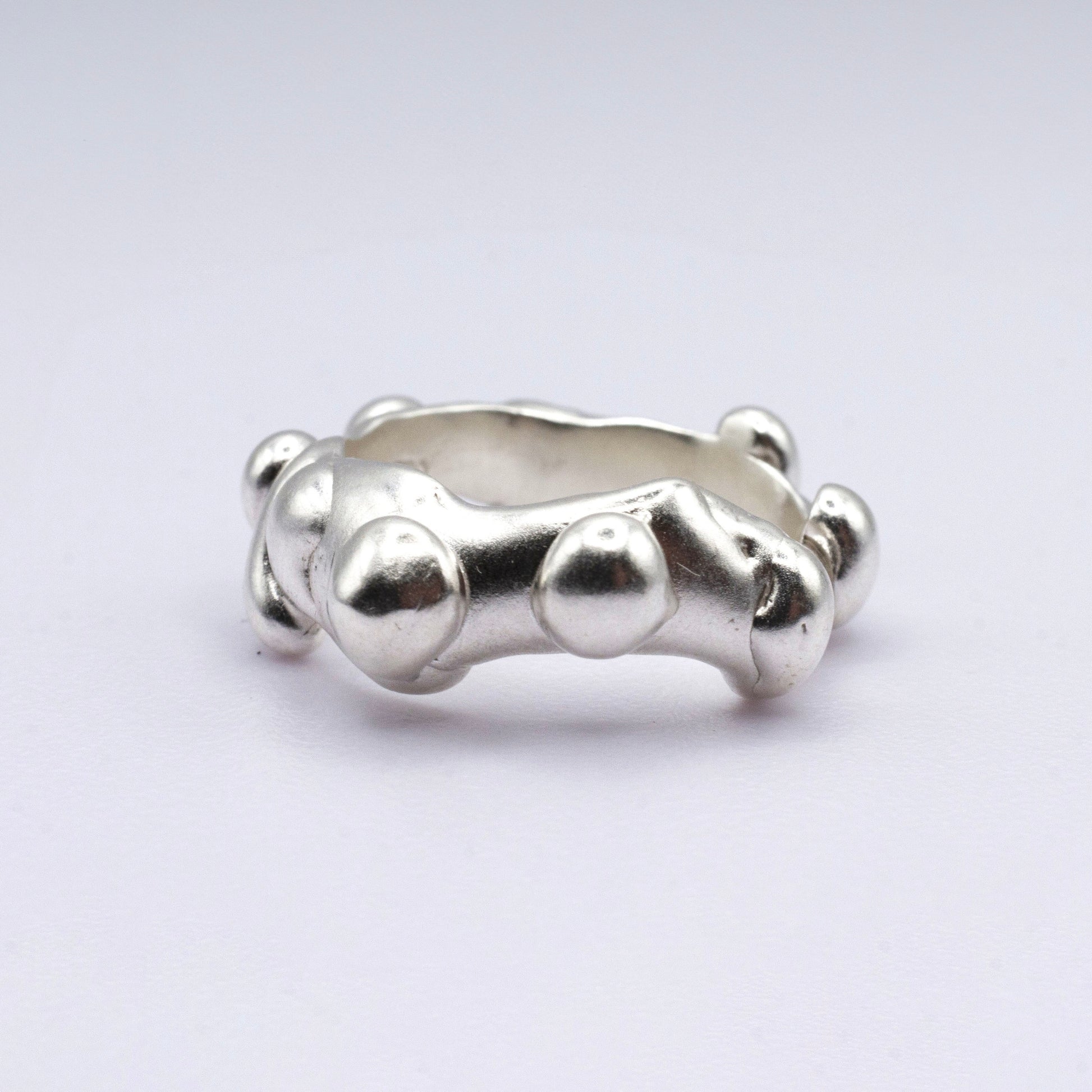 Silver ring with a unique design on a light gray background