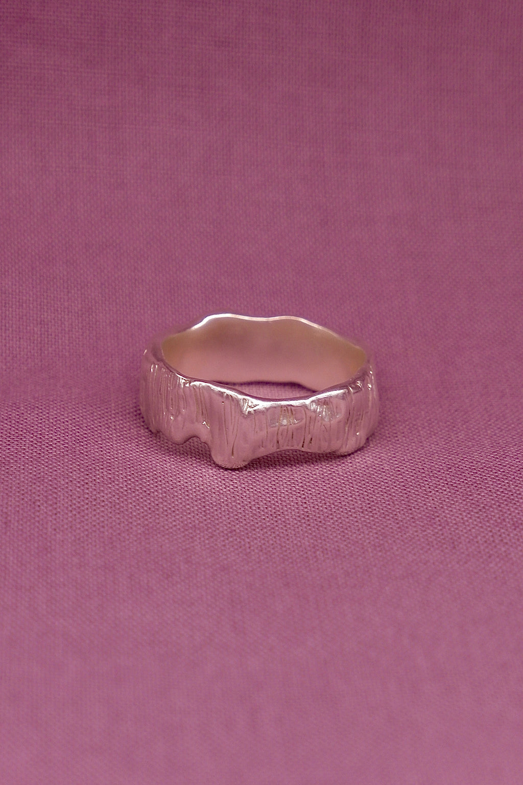 Silver ring on a pink fabric background