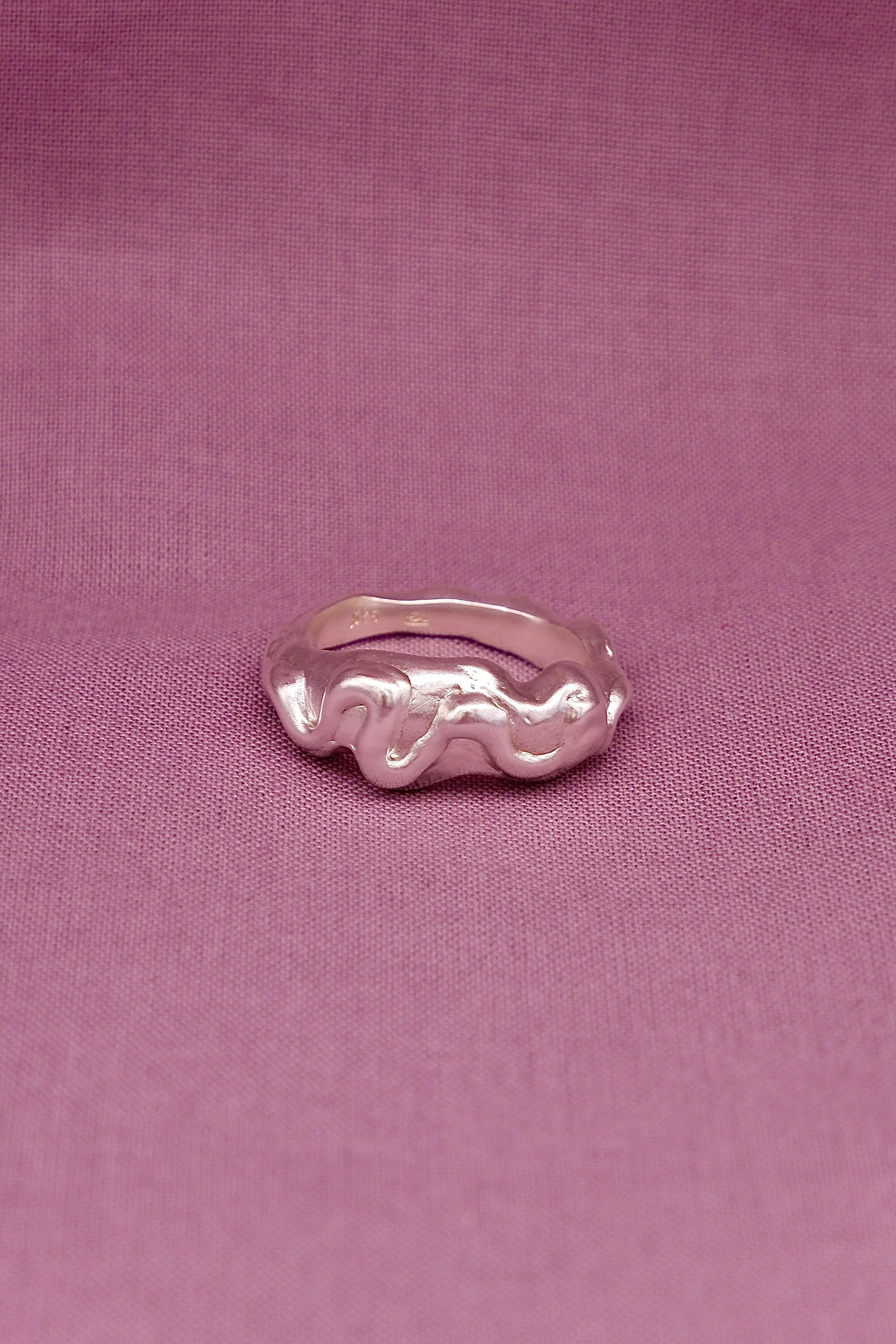 Silver ring on a pink fabric background