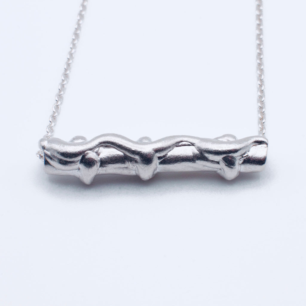 Silver branch-shaped pendant on a chain against a white background