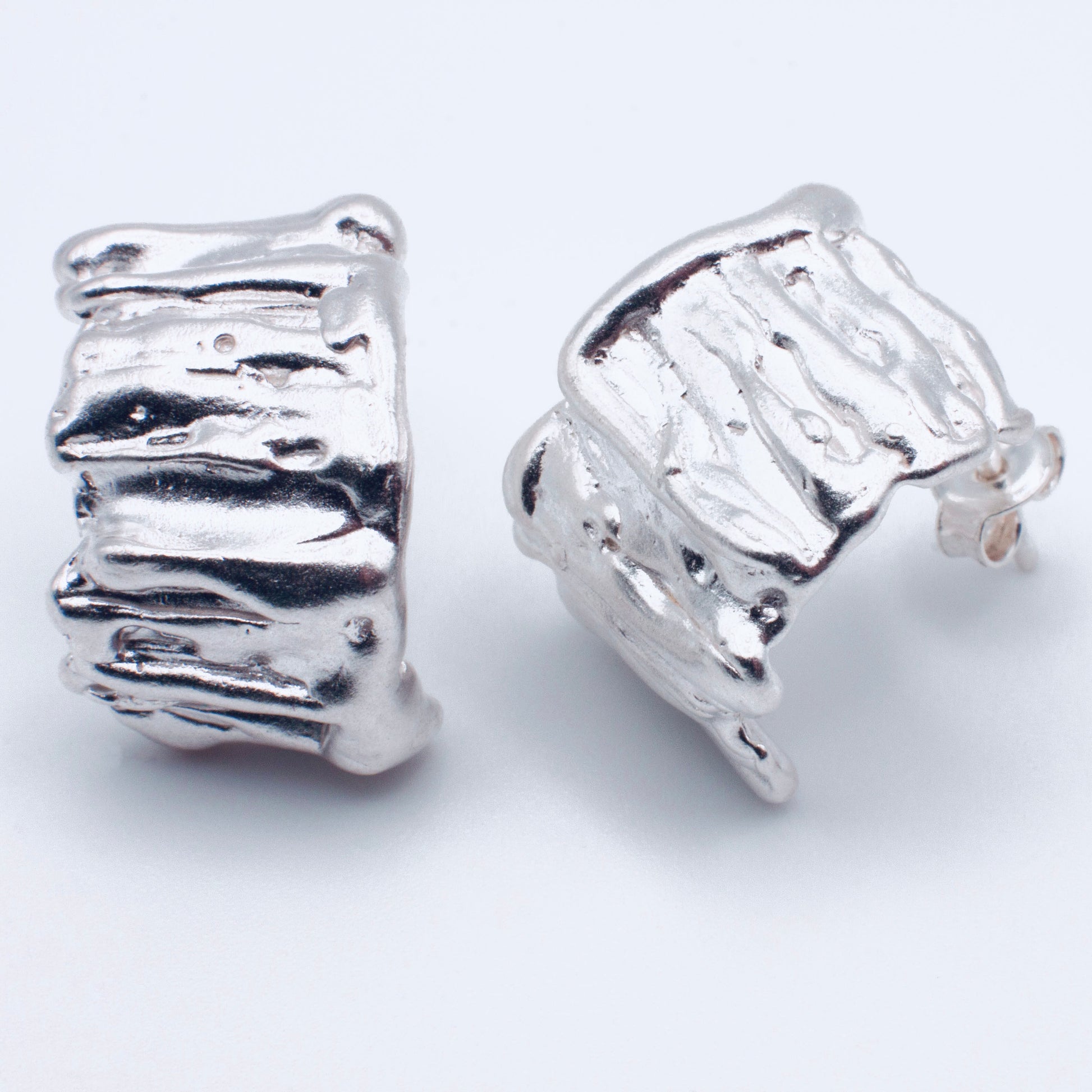 Pair of silver textured earrings on a white background