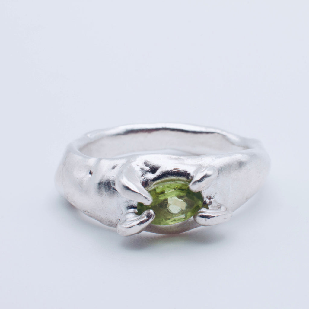 Silver ring with a green gemstone on a light gray background