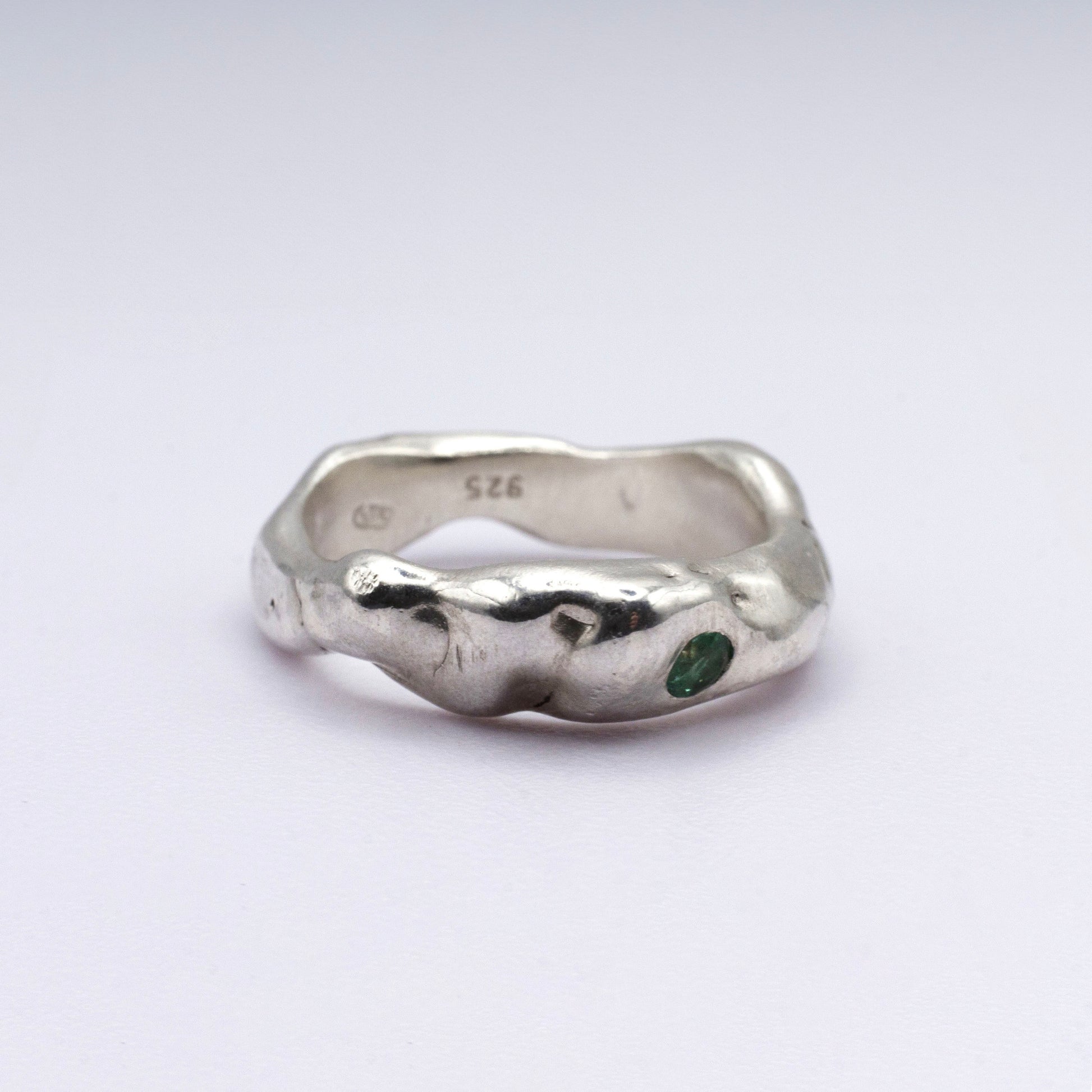 Silver ring with a green gemstone on a white background