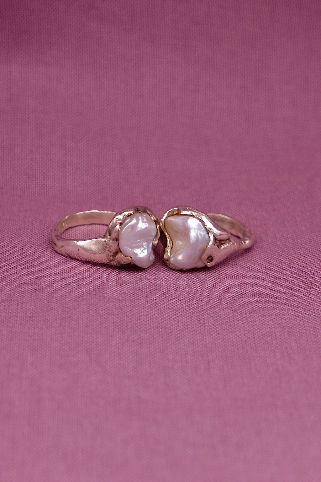 Silver ring pair with two pearls on a pink background