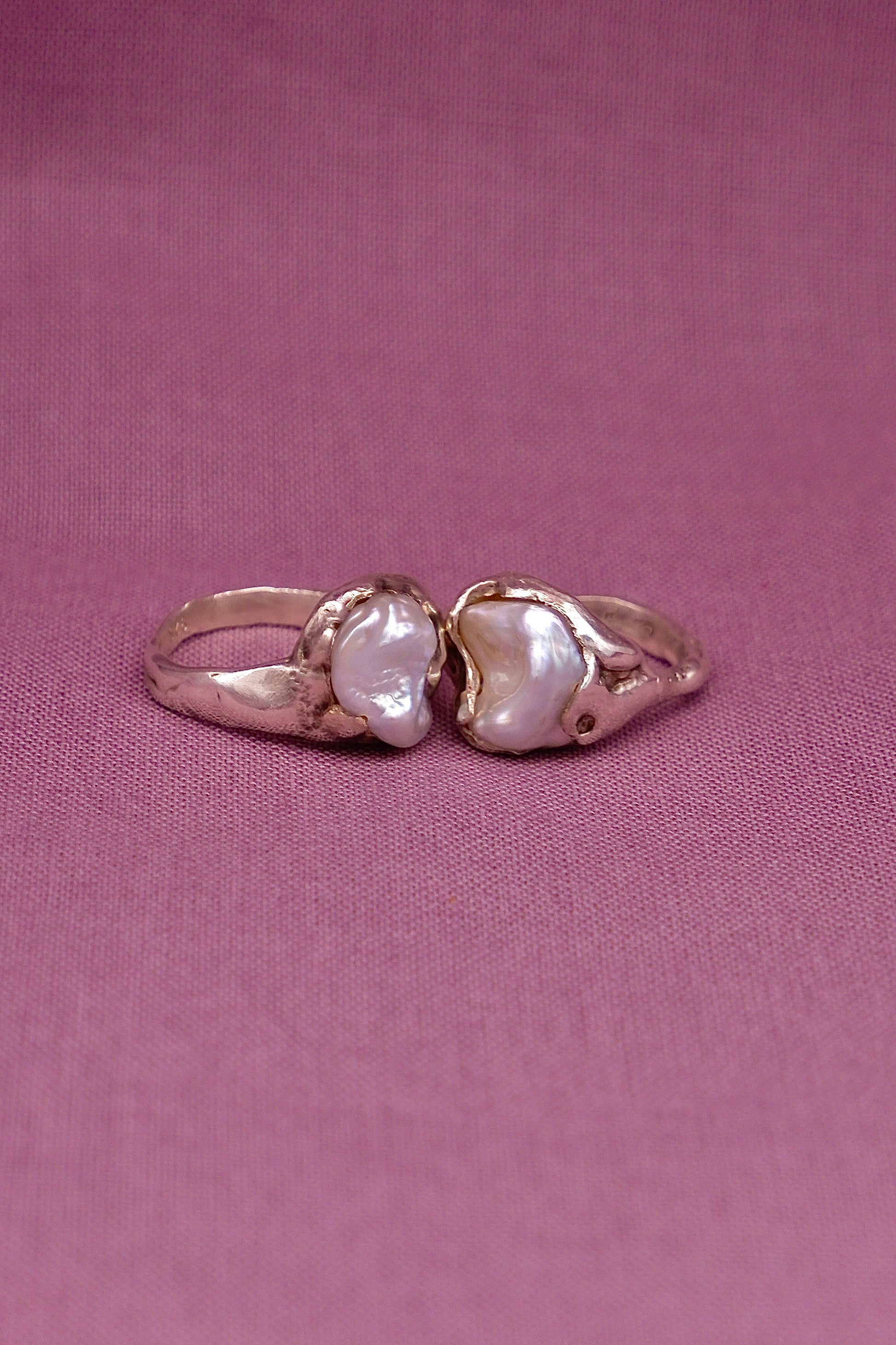 Silver ring pair with two pearls on a pink background