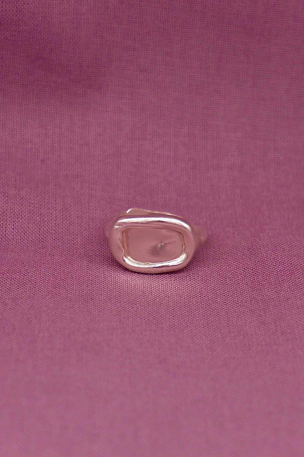 Silver ring on a pink fabric background