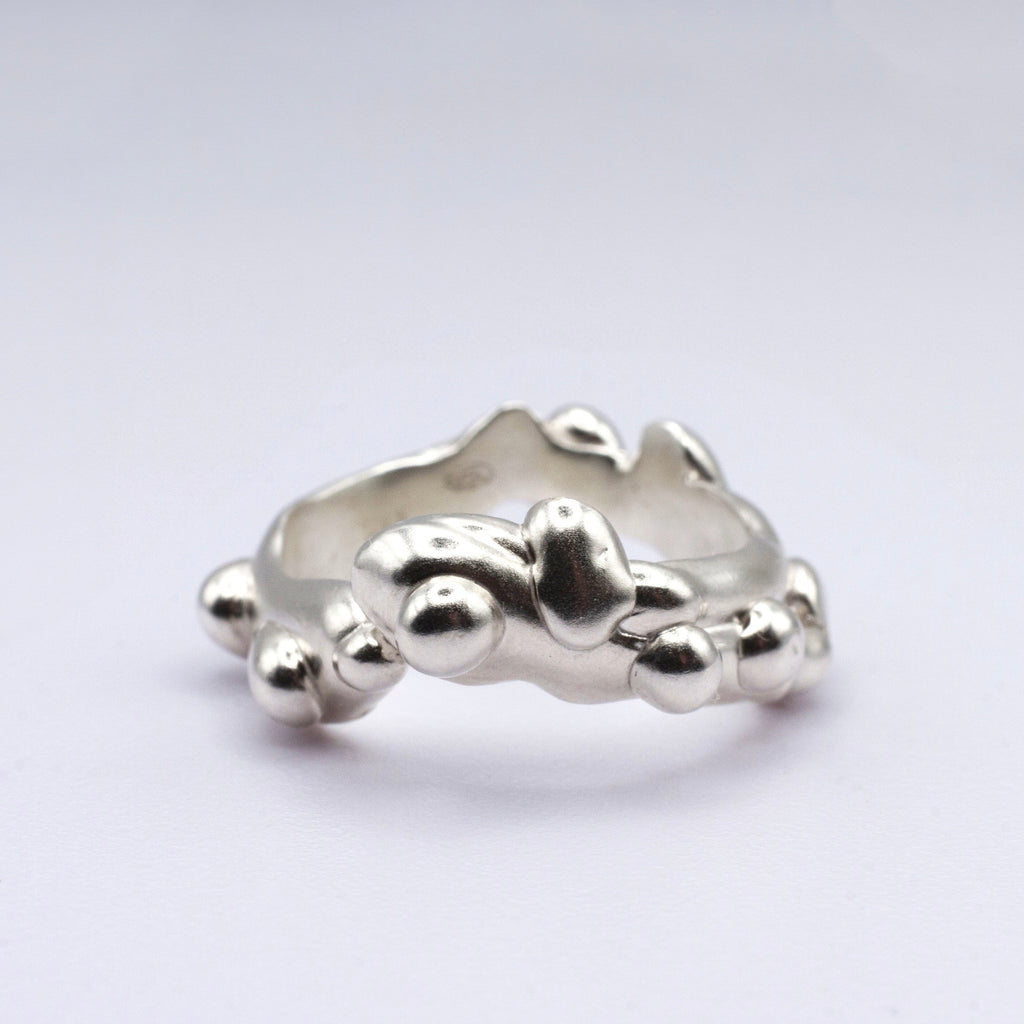 Silver ring with a unique design on a light gray background