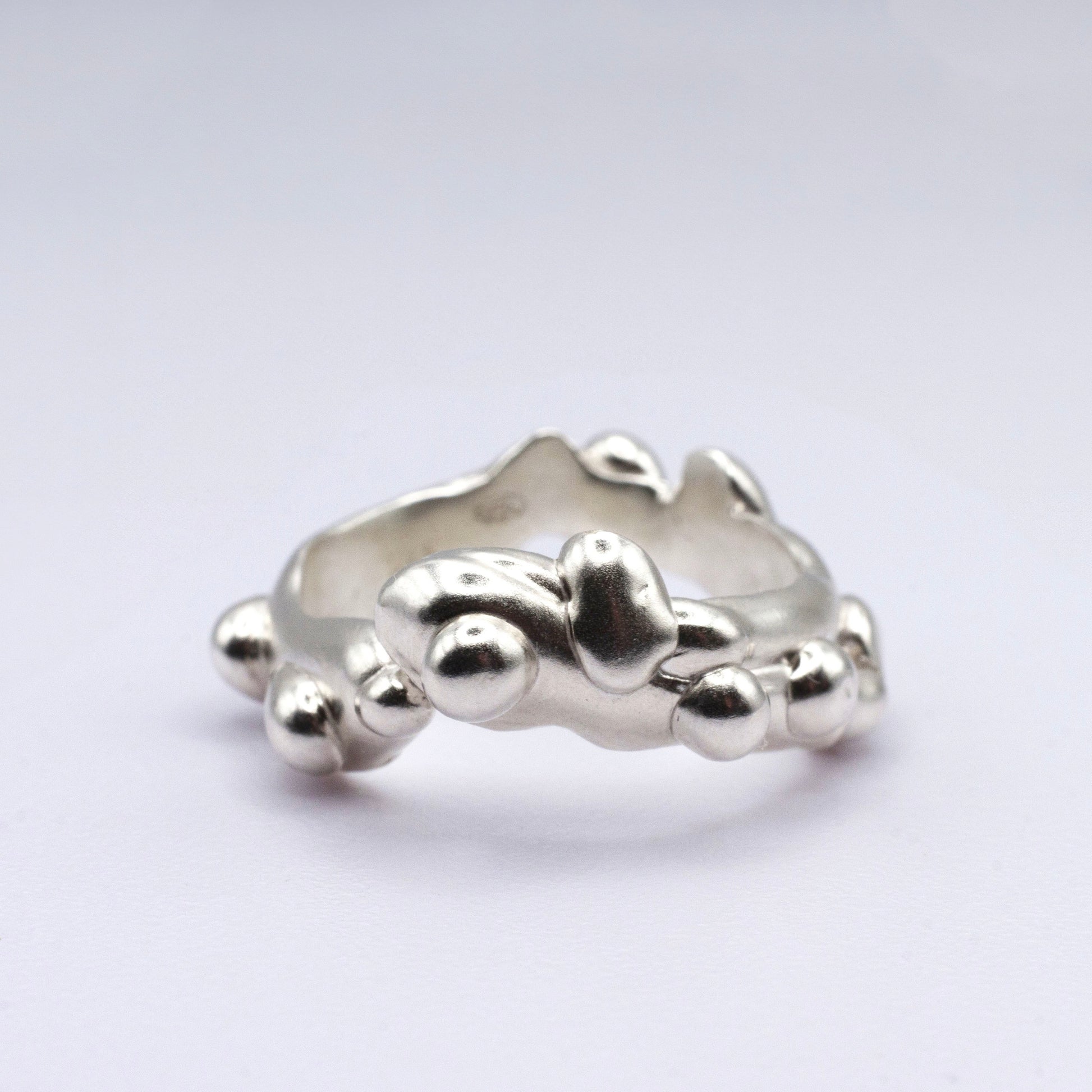 Silver ring with a unique design on a light gray background