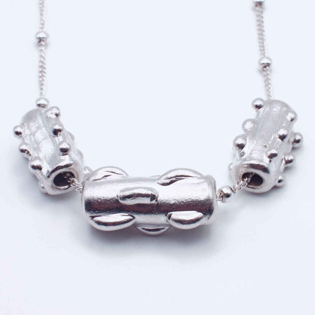 Silver necklace with cylindrical beads on a white background