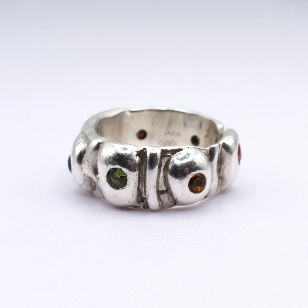 Silver ring with embedded gemstones on a white background