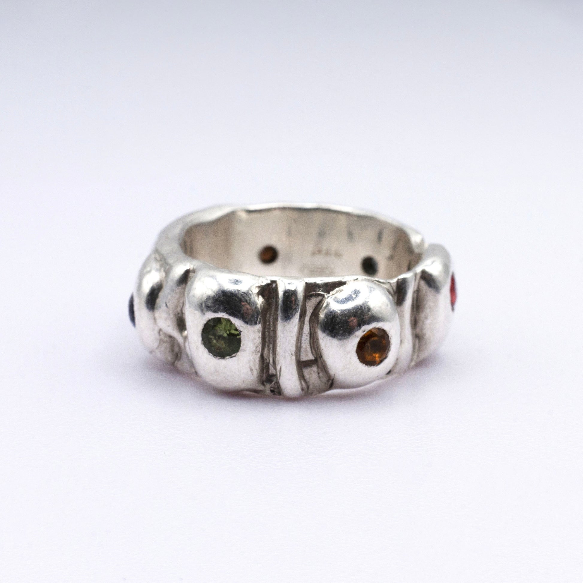 Silver ring with embedded gemstones on a white background