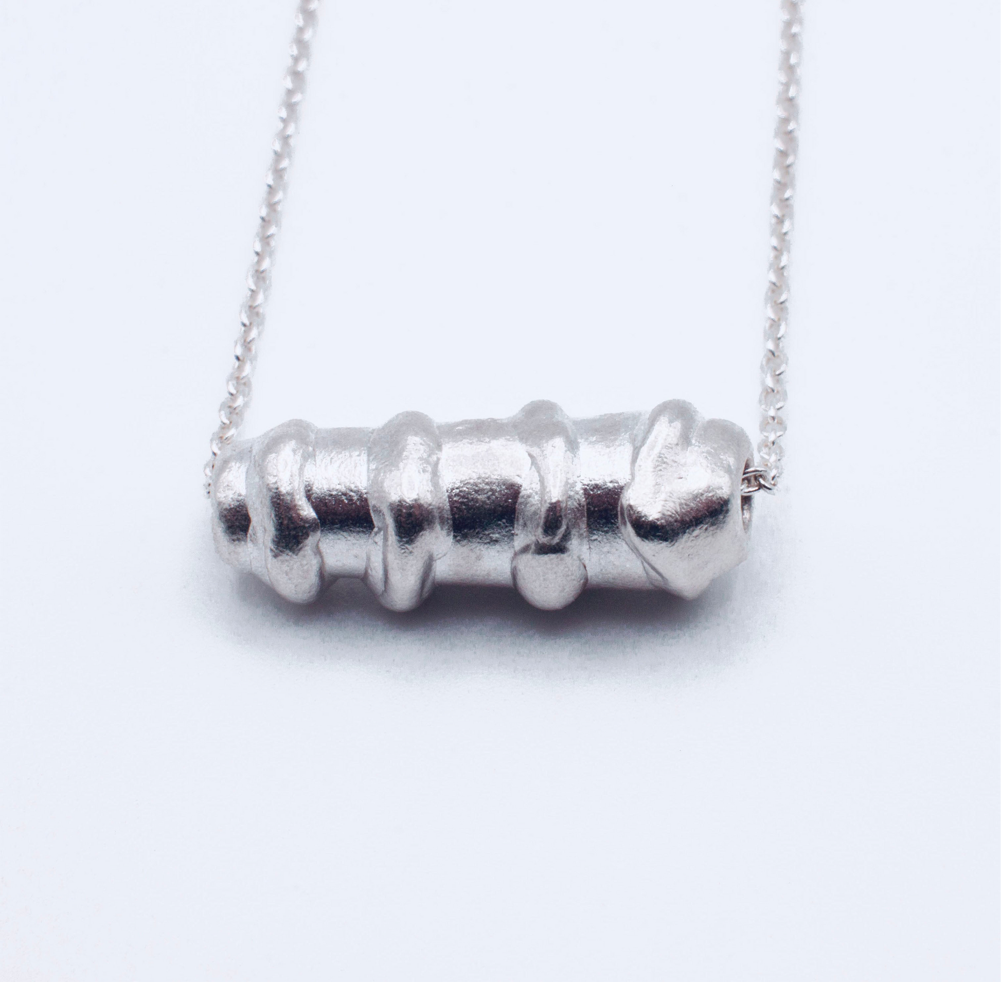 Silver cylindrical pendant bracelet on a white background